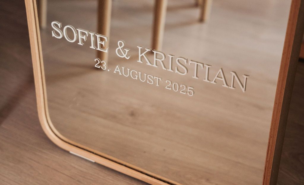 Close-up view of wooden signs with engraved text and dates displayed on a light wooden surface.