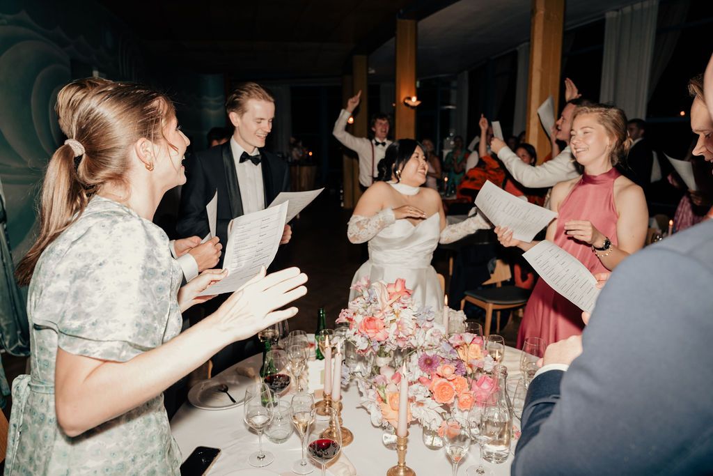 Wedding guests raise their glasses in celebration during an elegant reception dinner at a formal event.