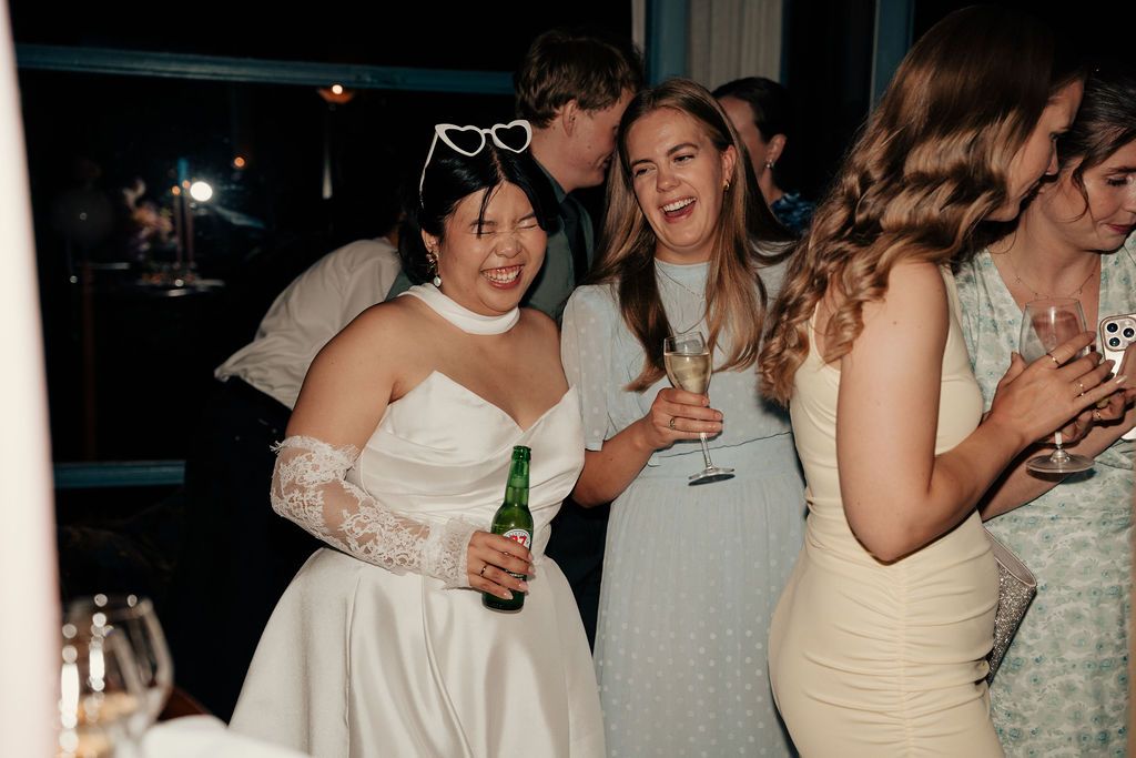 Wedding guests mingling and enjoying drinks at a dimly lit reception party.