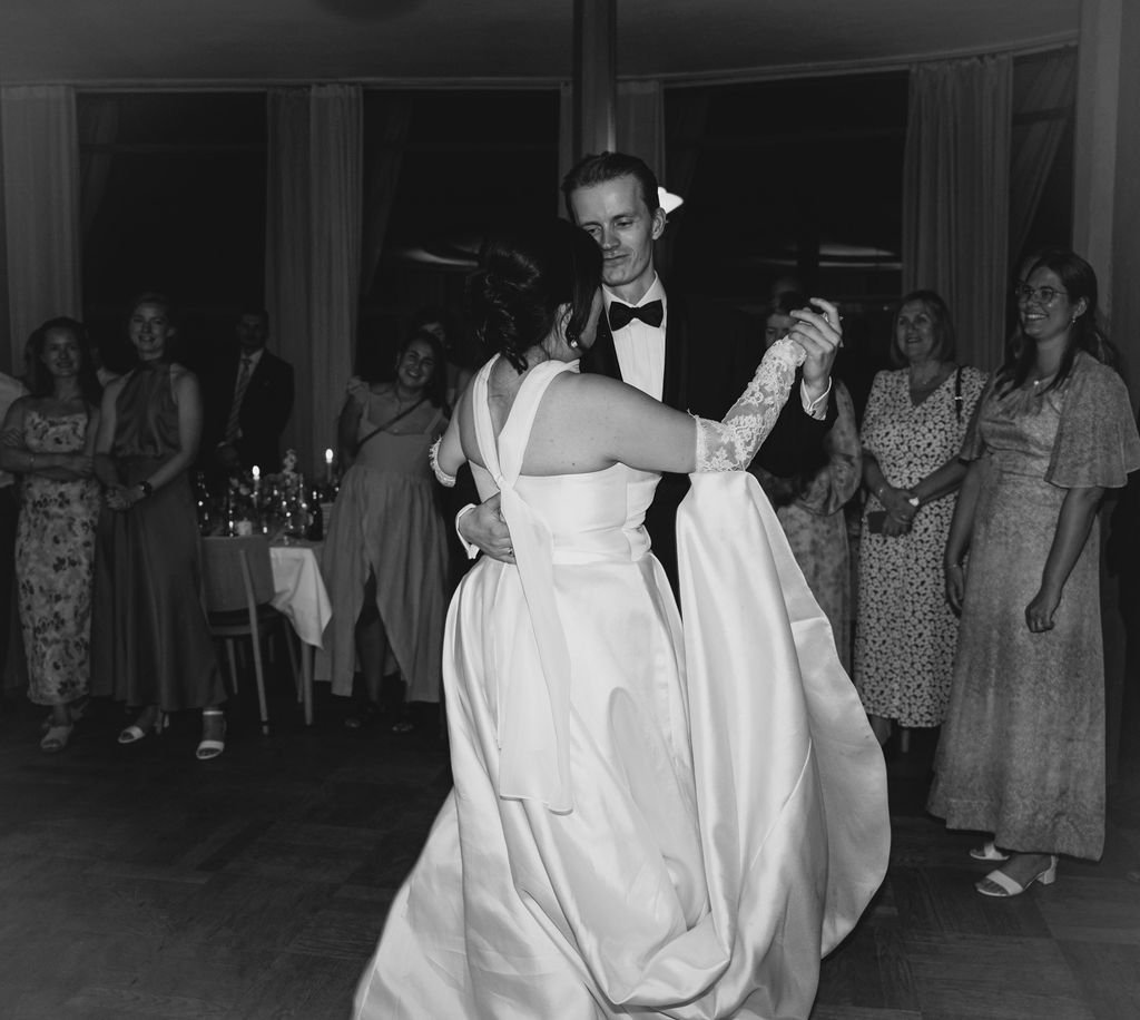 Black and white photo of couples dancing at a vintage social gathering in an indoor venue.