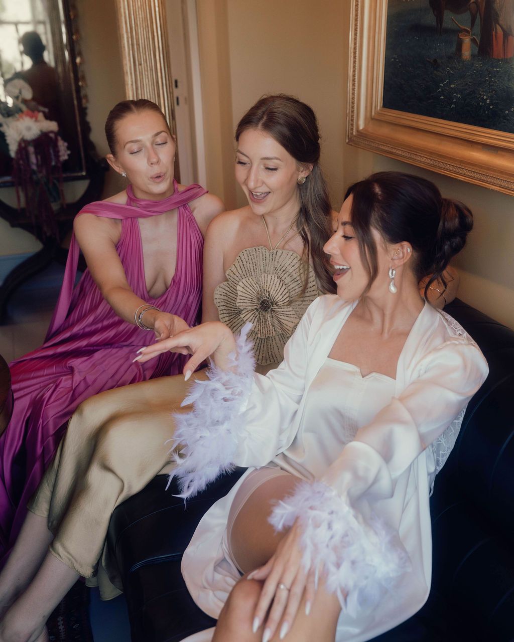 A group in formal attire laughs together while sitting in an elegant indoor setting.