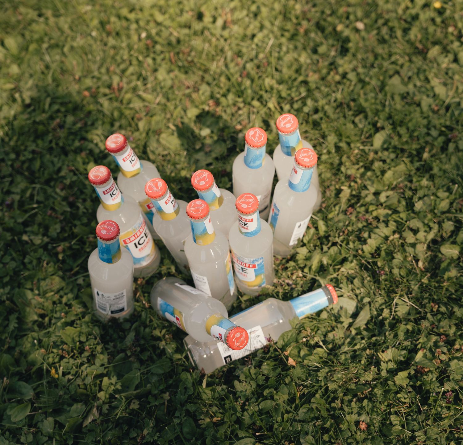 Multiple Smirnoff Ice bottles scattered on green grass at an outdoor wedding.