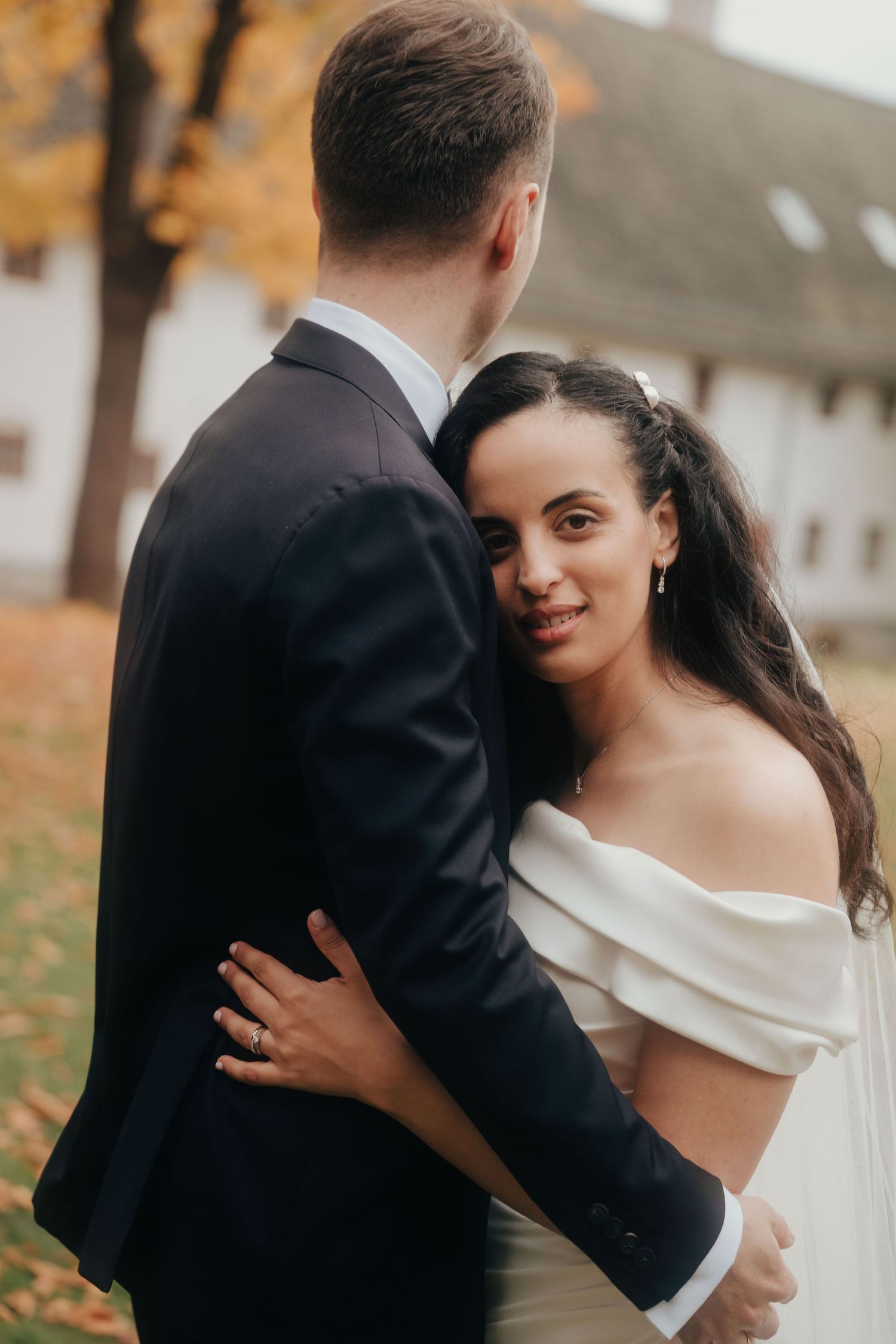 Romantic wedding couple embraces in an autumn setting with fallen leaves and soft natural lighting.