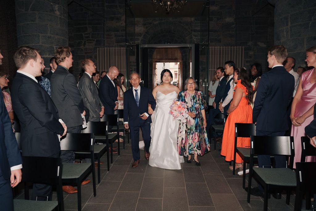 Wedding reception guests mingle and dance in a dimly lit venue with elegant decor and ambient lighting.