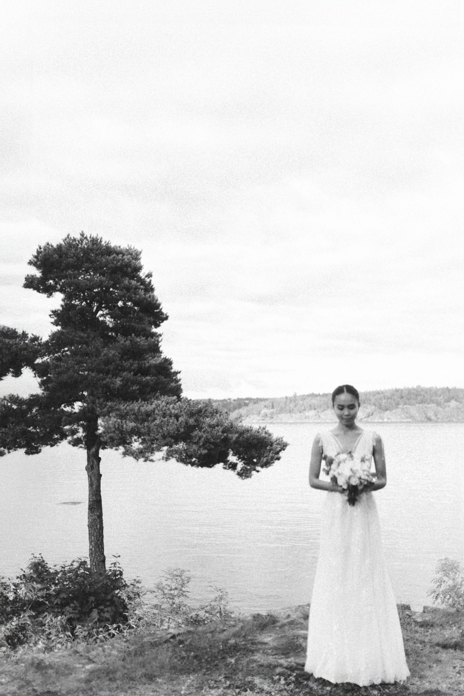 Four black and white photos show a scenic coastal landscape with pine trees and figures in white attire against the water.