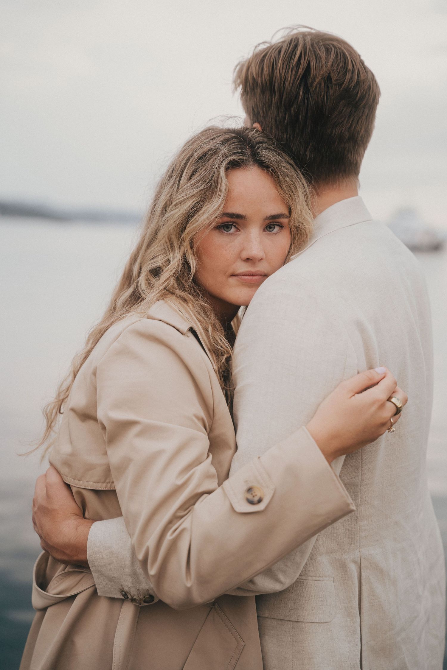 A couple in neutral tones share intimate embraces in a series of romantic outdoor portraits.