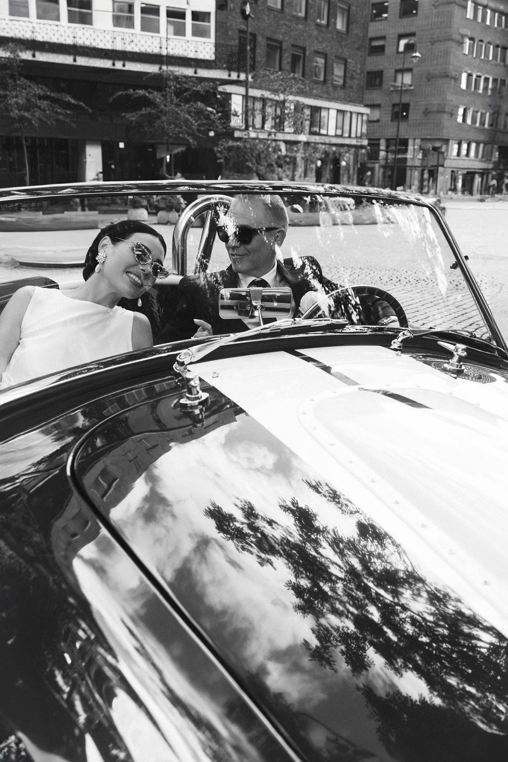 Vintage black and white photo of a classic convertible car with reflections on its polished hood.