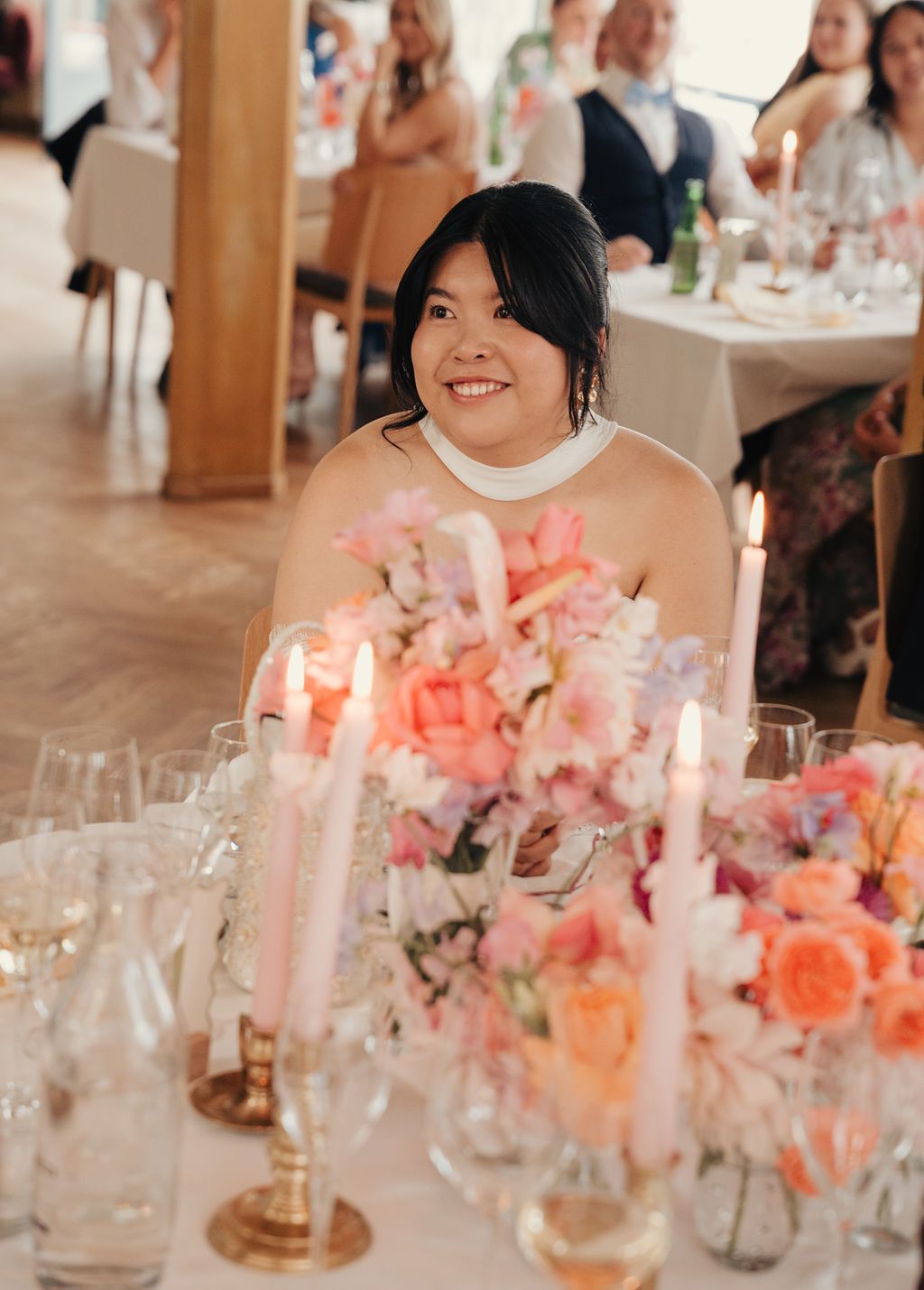 Elegant wedding reception table with pink floral centerpieces and glowing candles creating a romantic atmosphere.