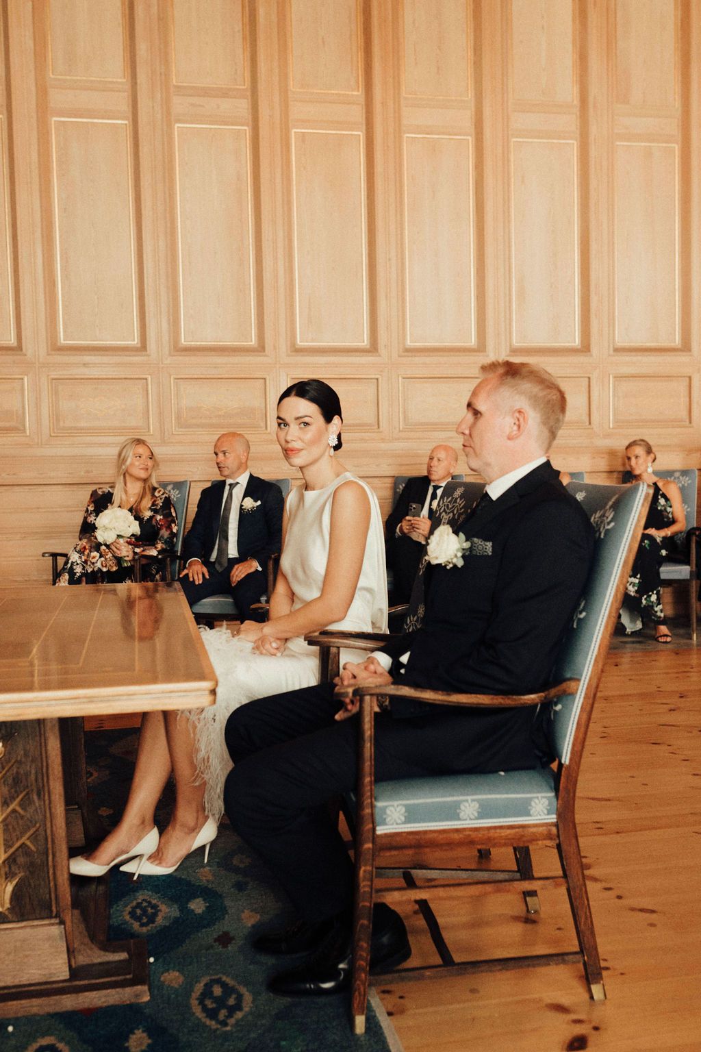 Wedding reception scene in an elegant wood-paneled room with formal seating arrangements.