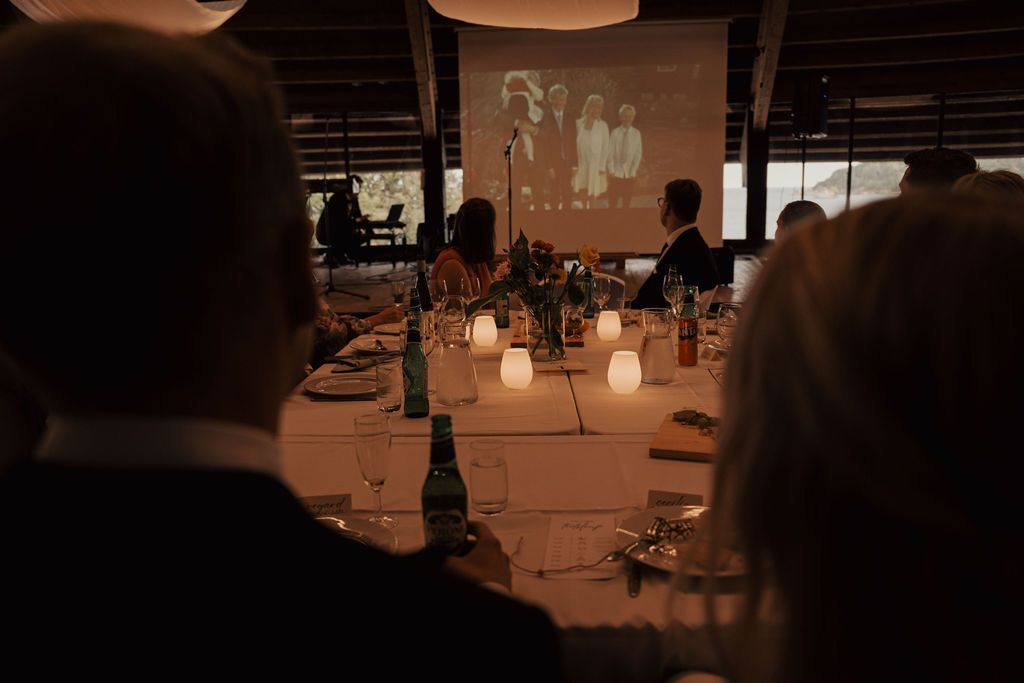 Candlelit tables set for an elegant evening reception with glowing ambiance in a dimly lit venue.