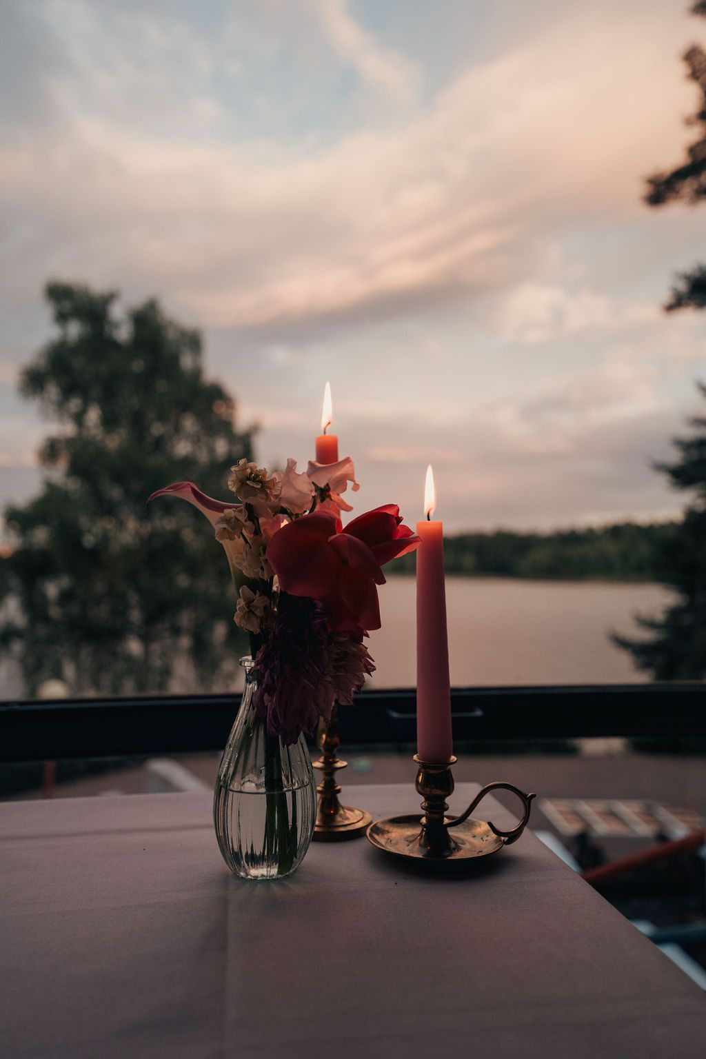 Lit burgundy candles and a small floral arrangement create an intimate ambiance at dusk.