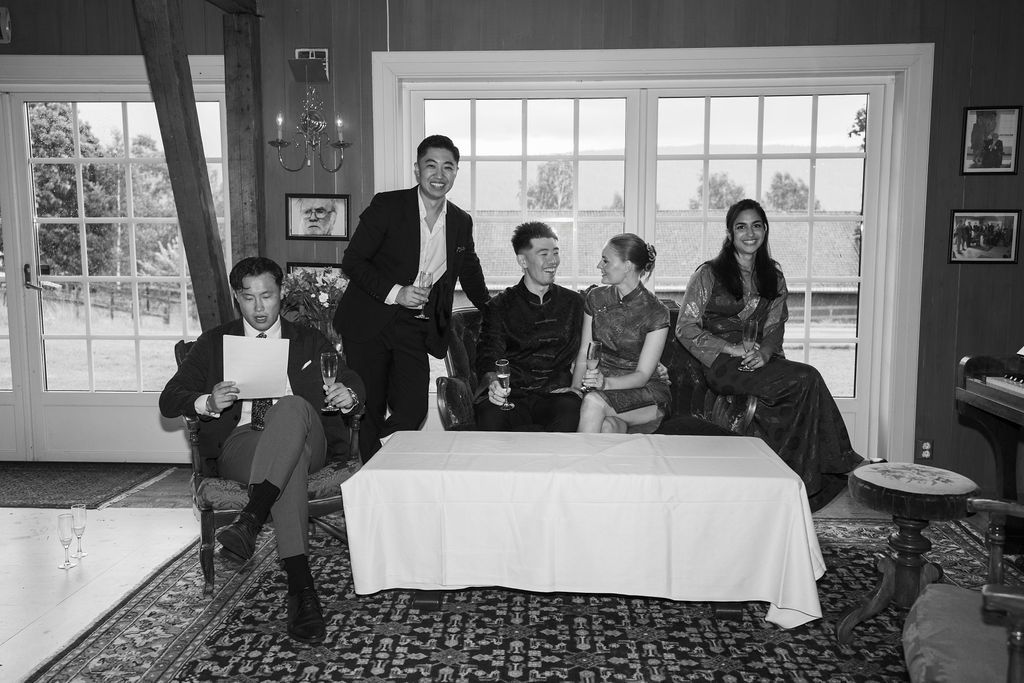A black and white panoramic photo shows people gathered at tables in a formal dining room setting.
