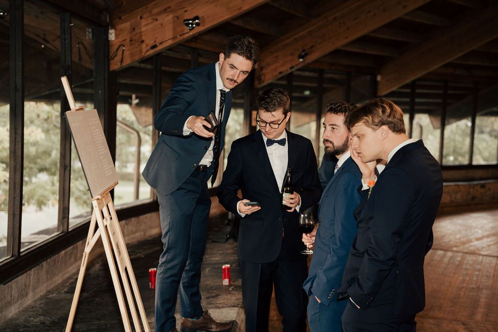 Wedding party in formal attire gathers in rustic wooden venue with exposed beams and natural lighting.
