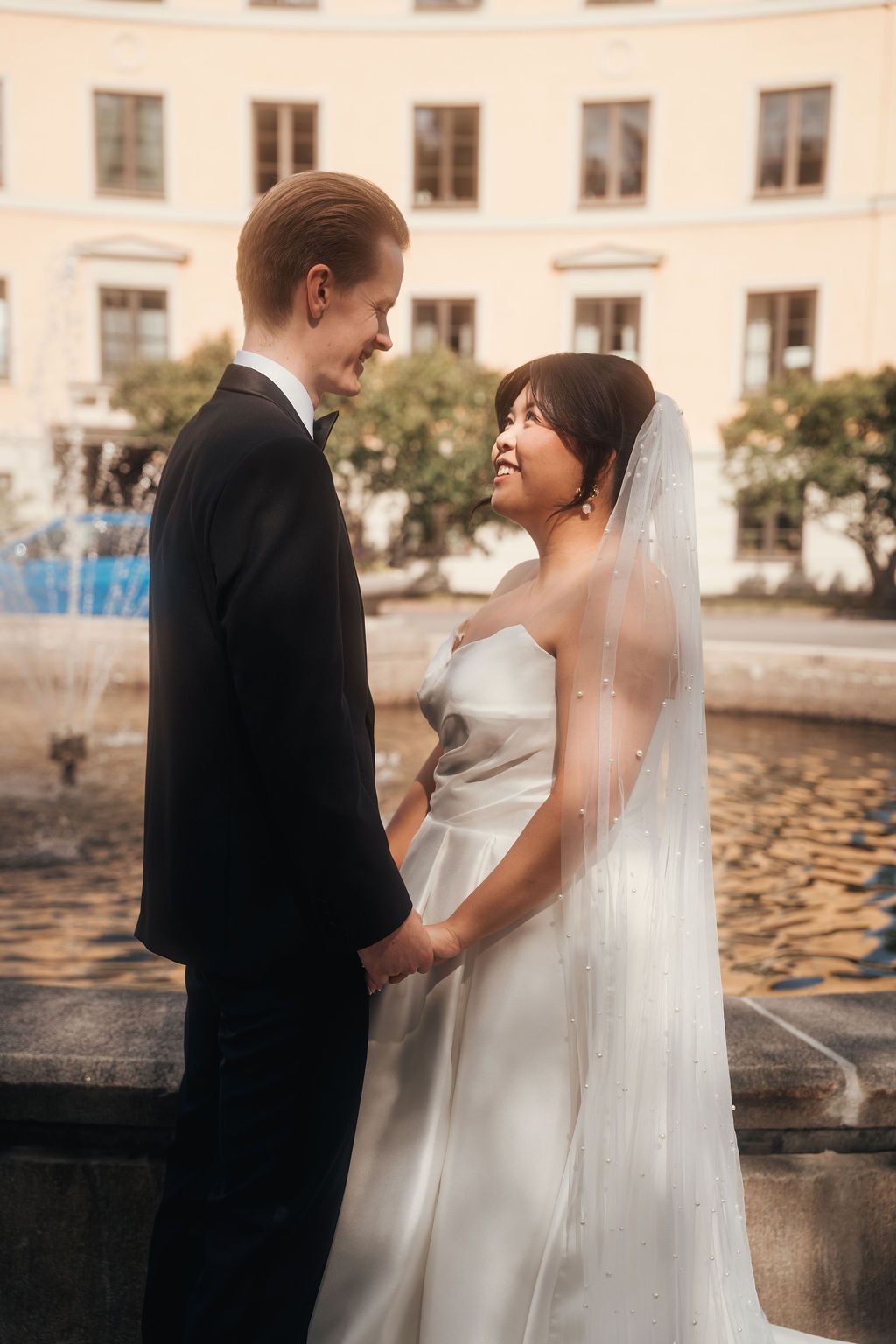 A romantic wedding couple shares tender moments by a waterfront during their outdoor photo session.