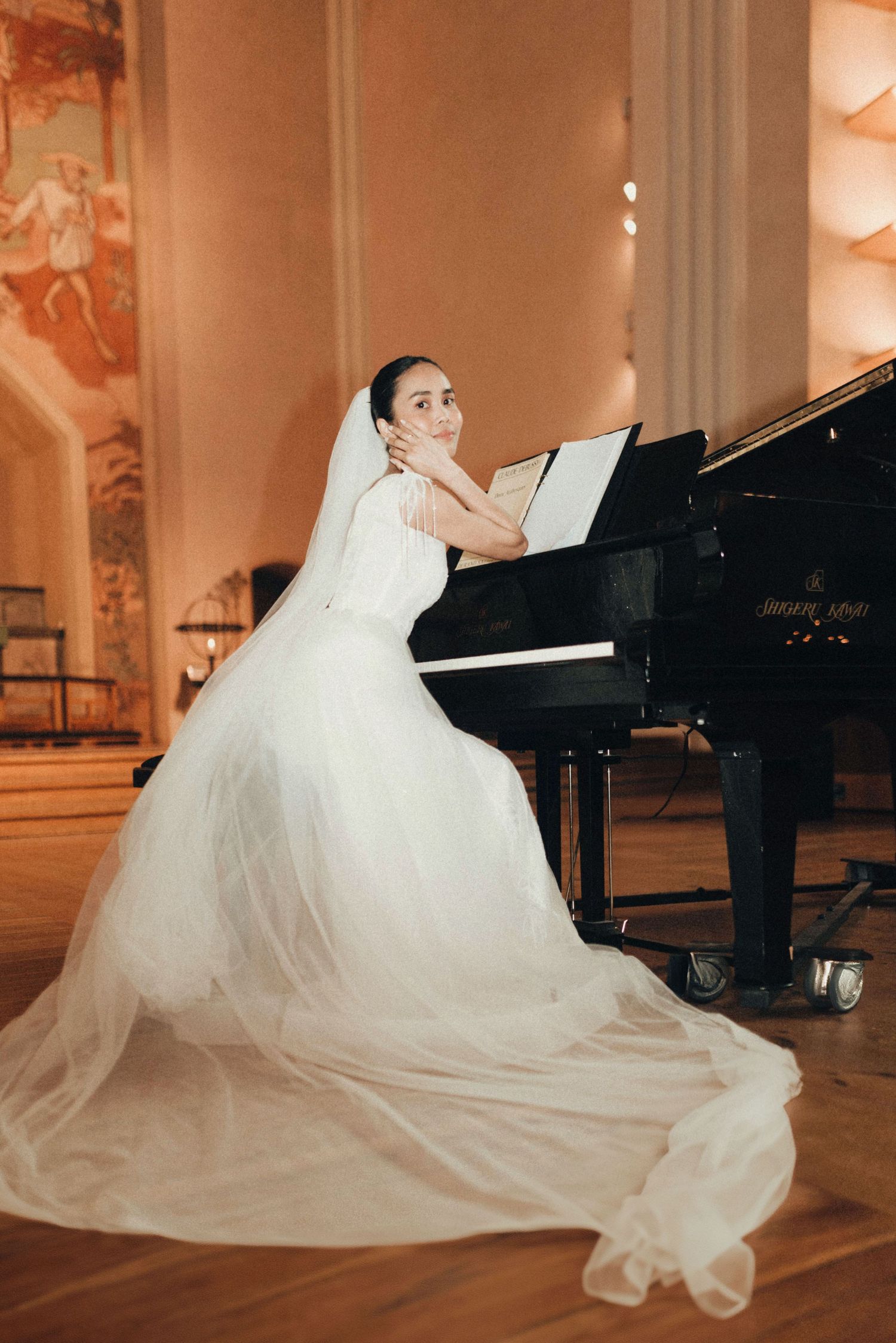 A warm-toned photo sequence featuring a bride in a flowing veil posing with a grand piano in an elegant setting.