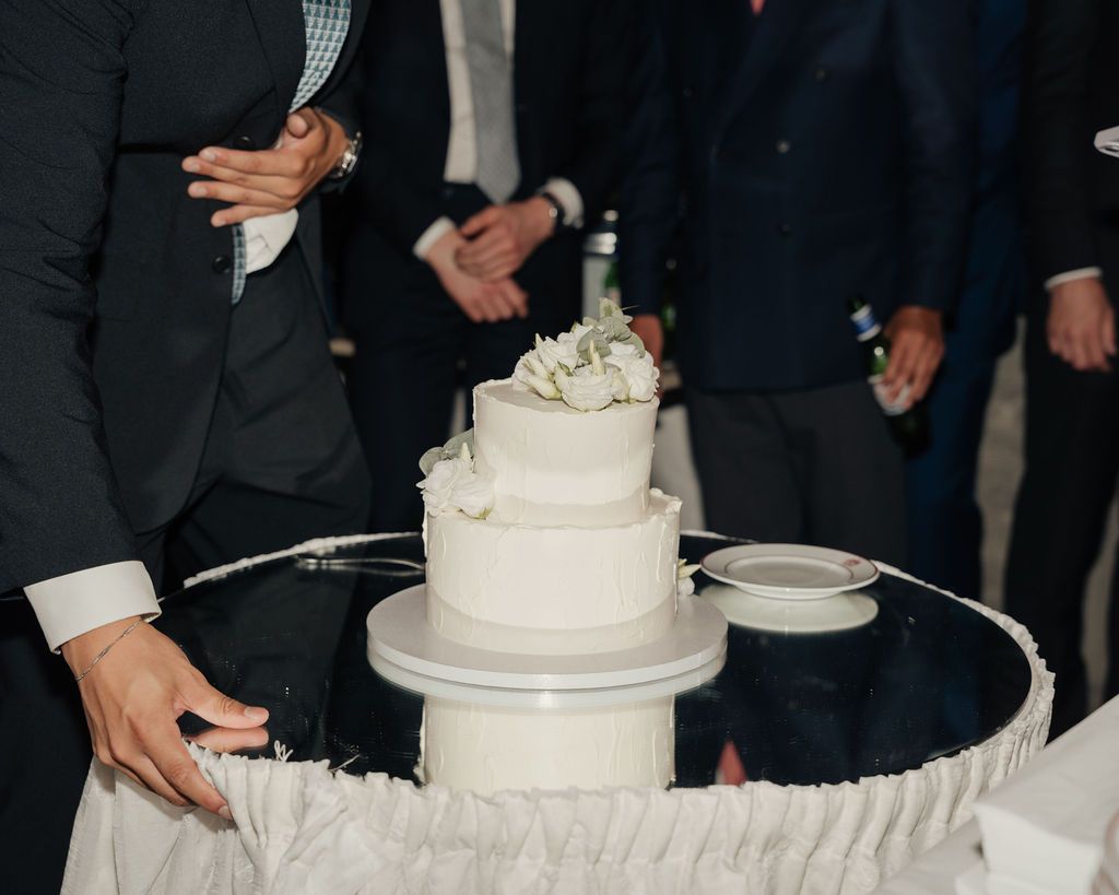 White tiered wedding cake displayed on an elegant table at a reception.