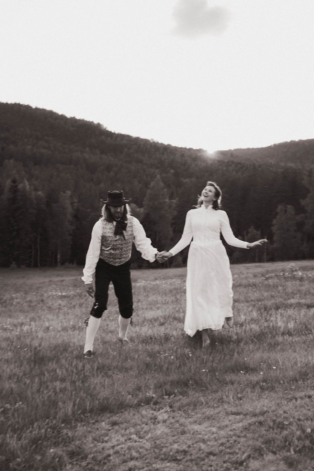 A playful black and white sequence of a couple dancing and spinning together in a rural field with hills in background.