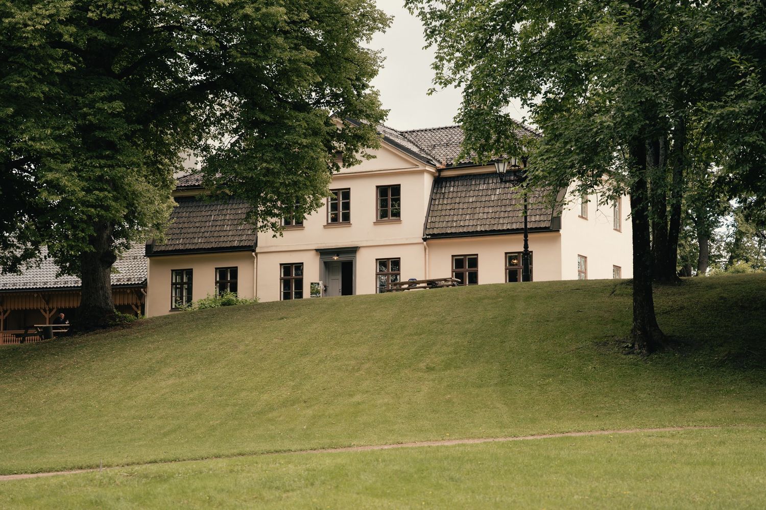 White country estate wedding venue surrounded by mature trees on a lush green hillside.