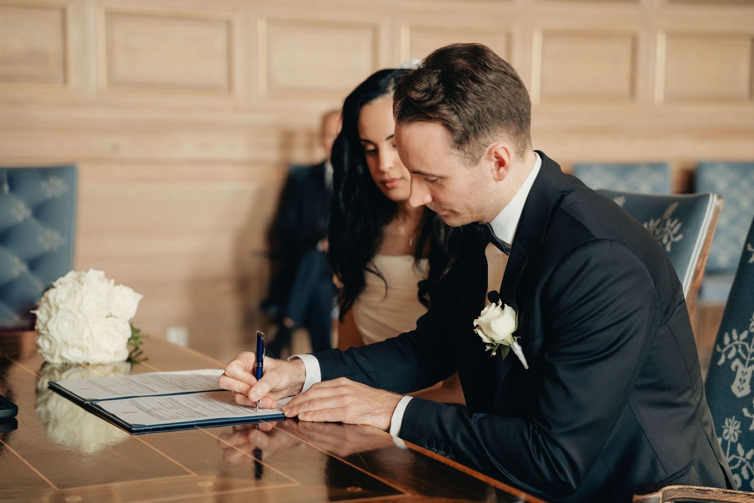 A series of four photos showing wedding document signing moments in formal attire at an elegant indoor venue.