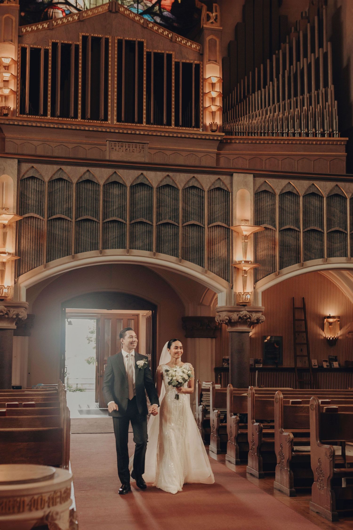 A couple shares intimate moments in a grand historic church venue with ornate architectural details and warm lighting.