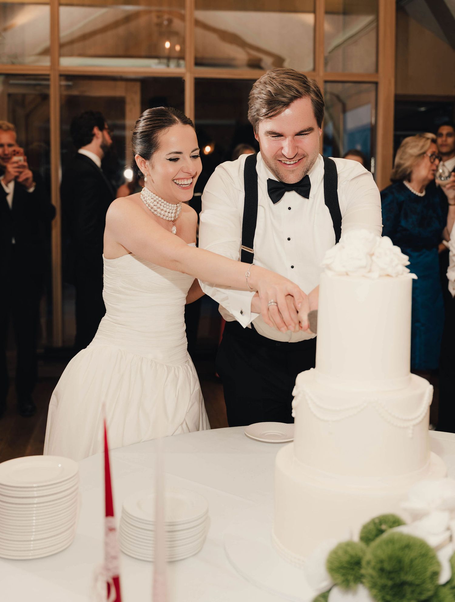 Bride and groom cutting a white three-tier wedding cake at their elegant reception.