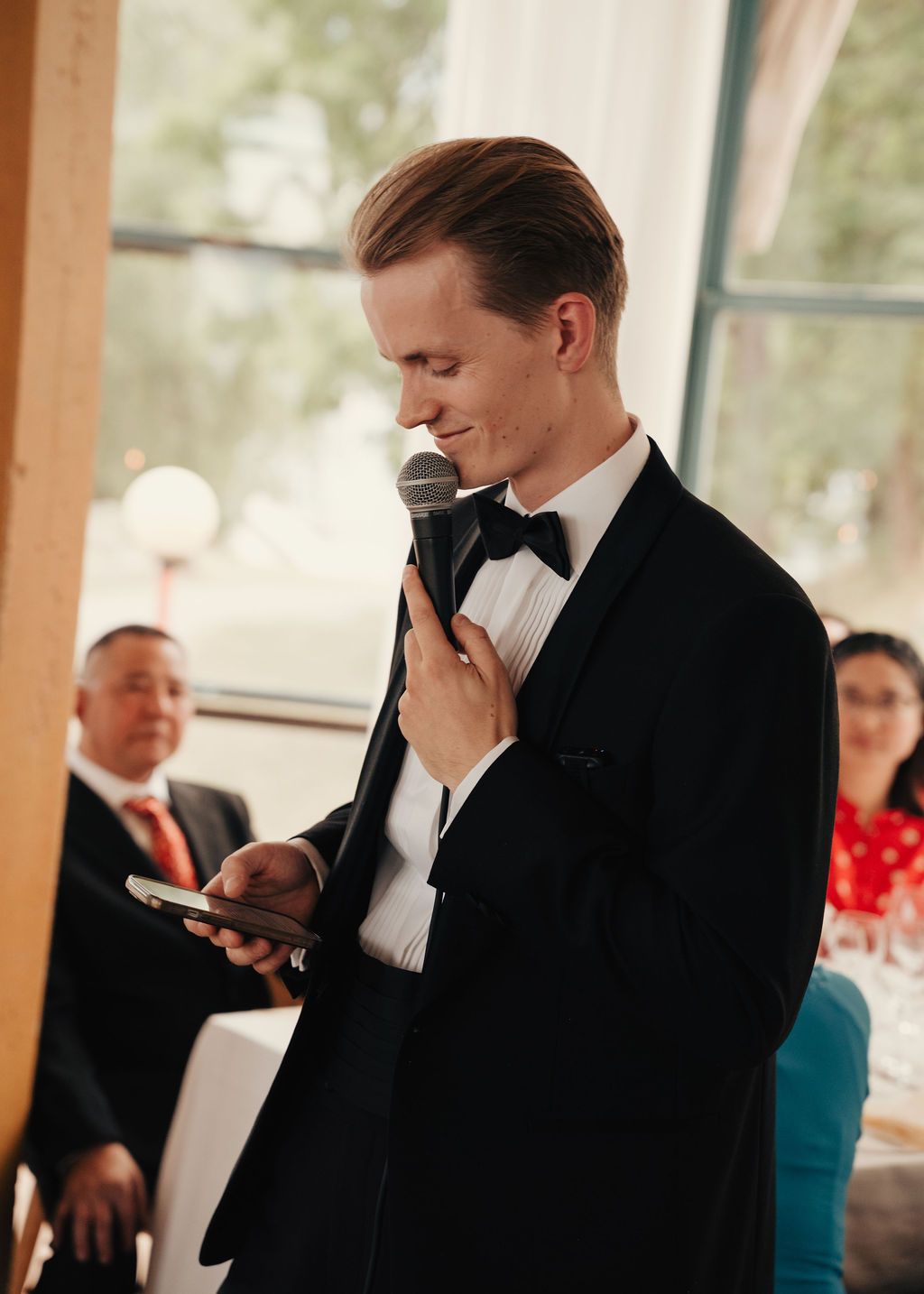 Groomsmen in black tuxedos wipe tears during an emotional wedding ceremony.