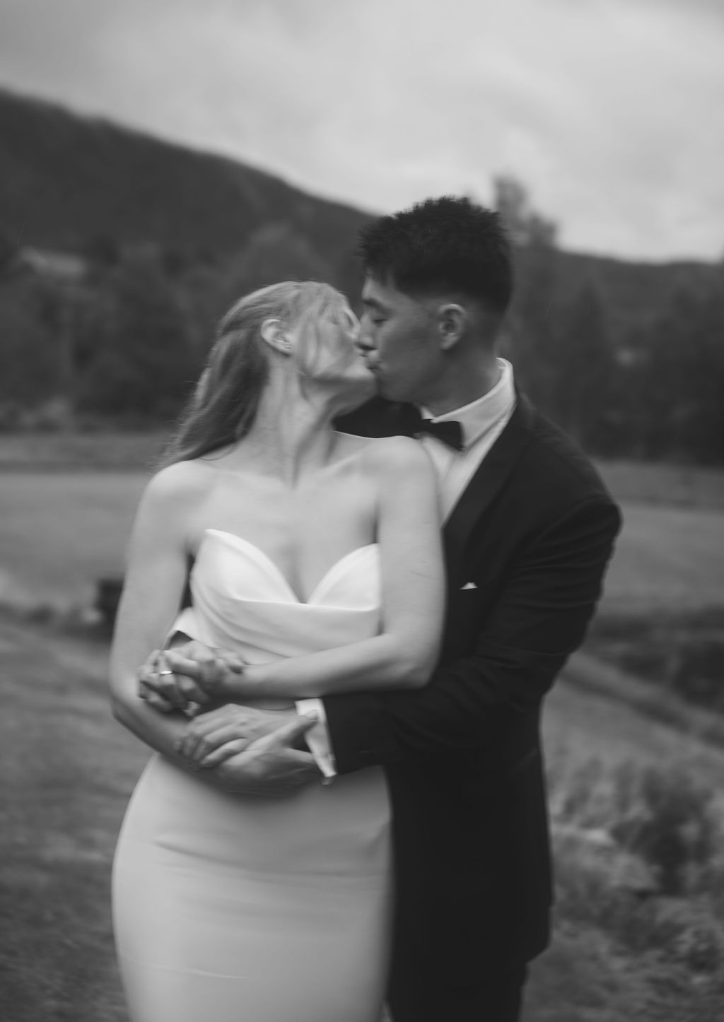 A romantic black and white wedding photo series showing tender moments between a couple in an outdoor setting.