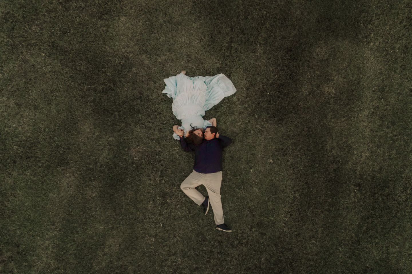 A collection of scattered clothing items and personal belongings arranged on a dark surface.
