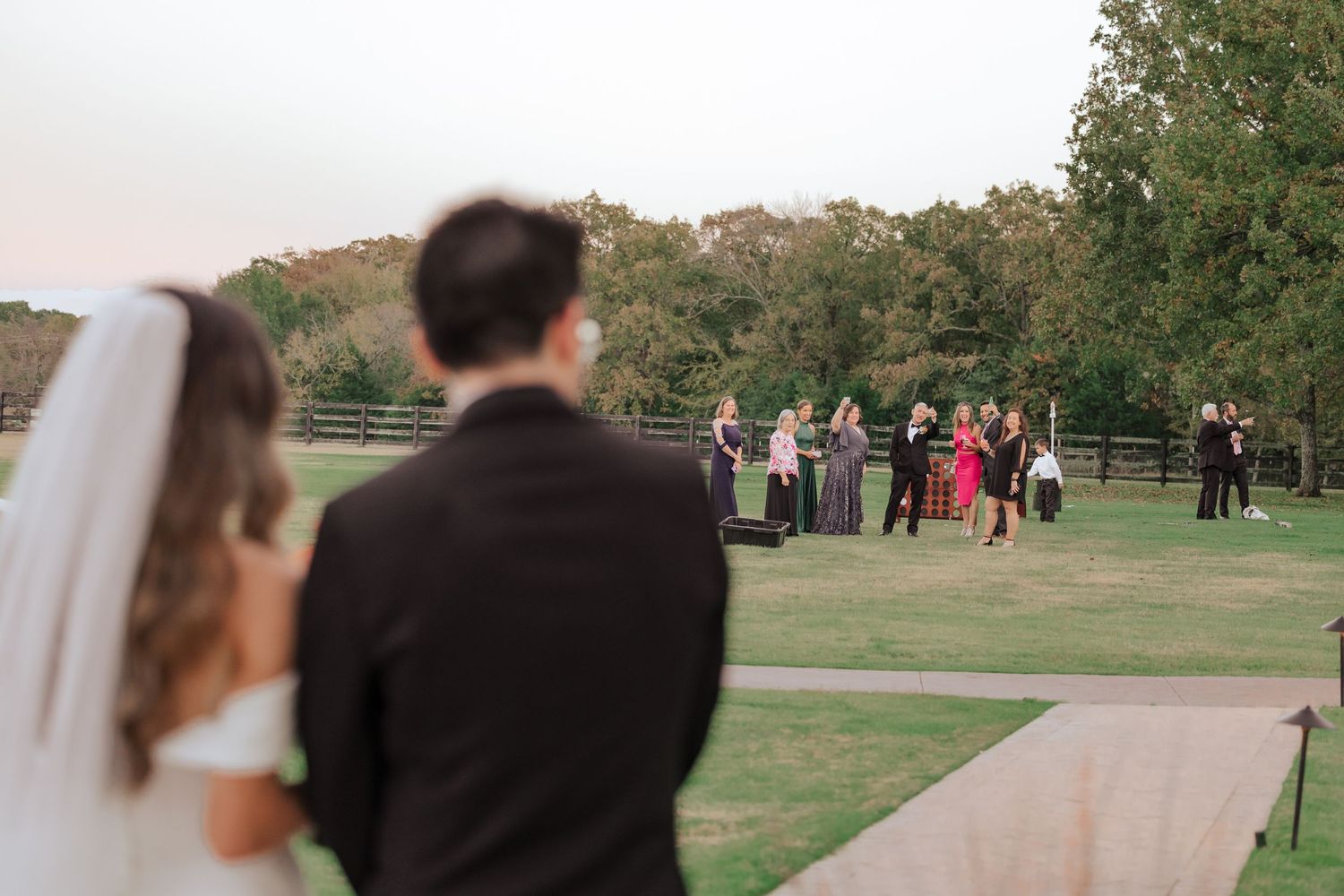 Wedding guests gather on a path in a scenic outdoor venue during an autumn celebration.