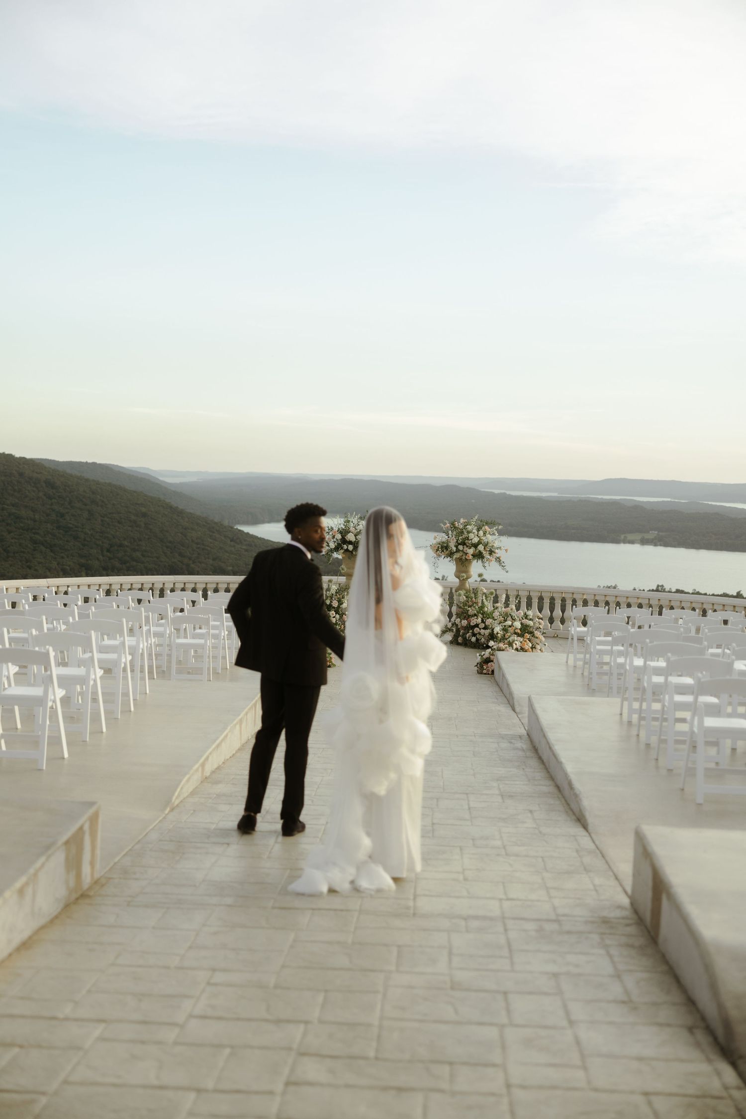 Bride and groom stand on elegant outdoor terrace wedding venue overlooking scenic lake at Stone Haven Wedding Venue in Section Alabama