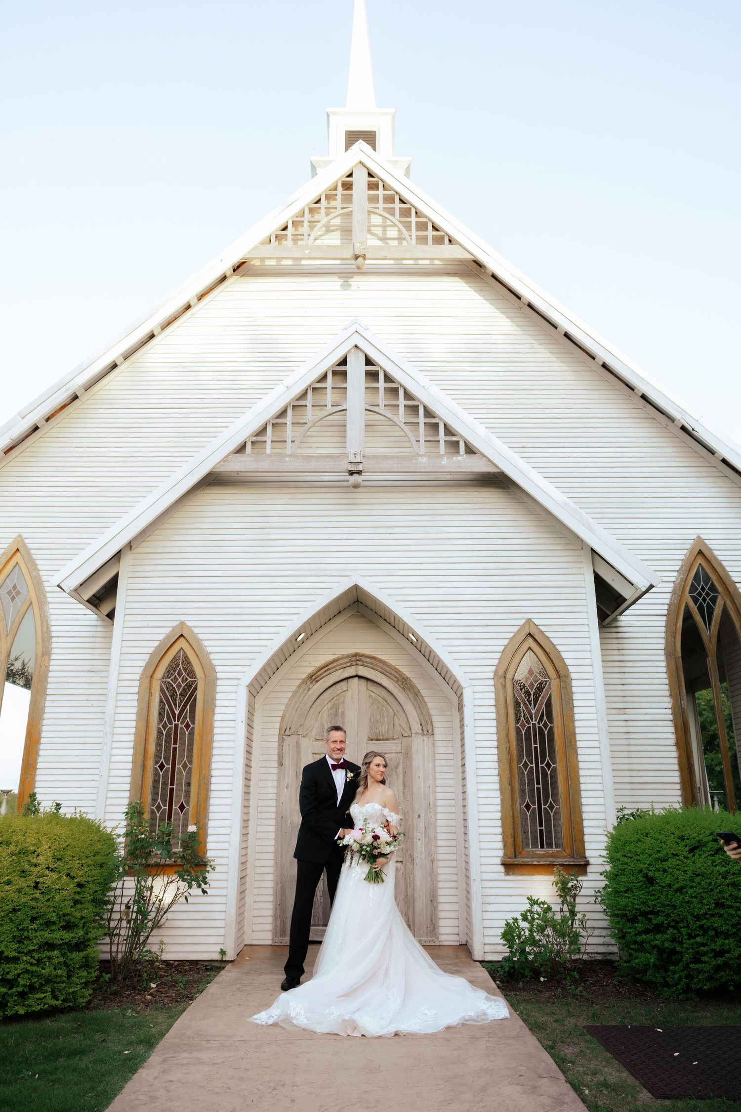 A sequence of wedding photos in front of a white chapel with Gothic arched windows and doors taken by dallas wedding photographer Jocy
