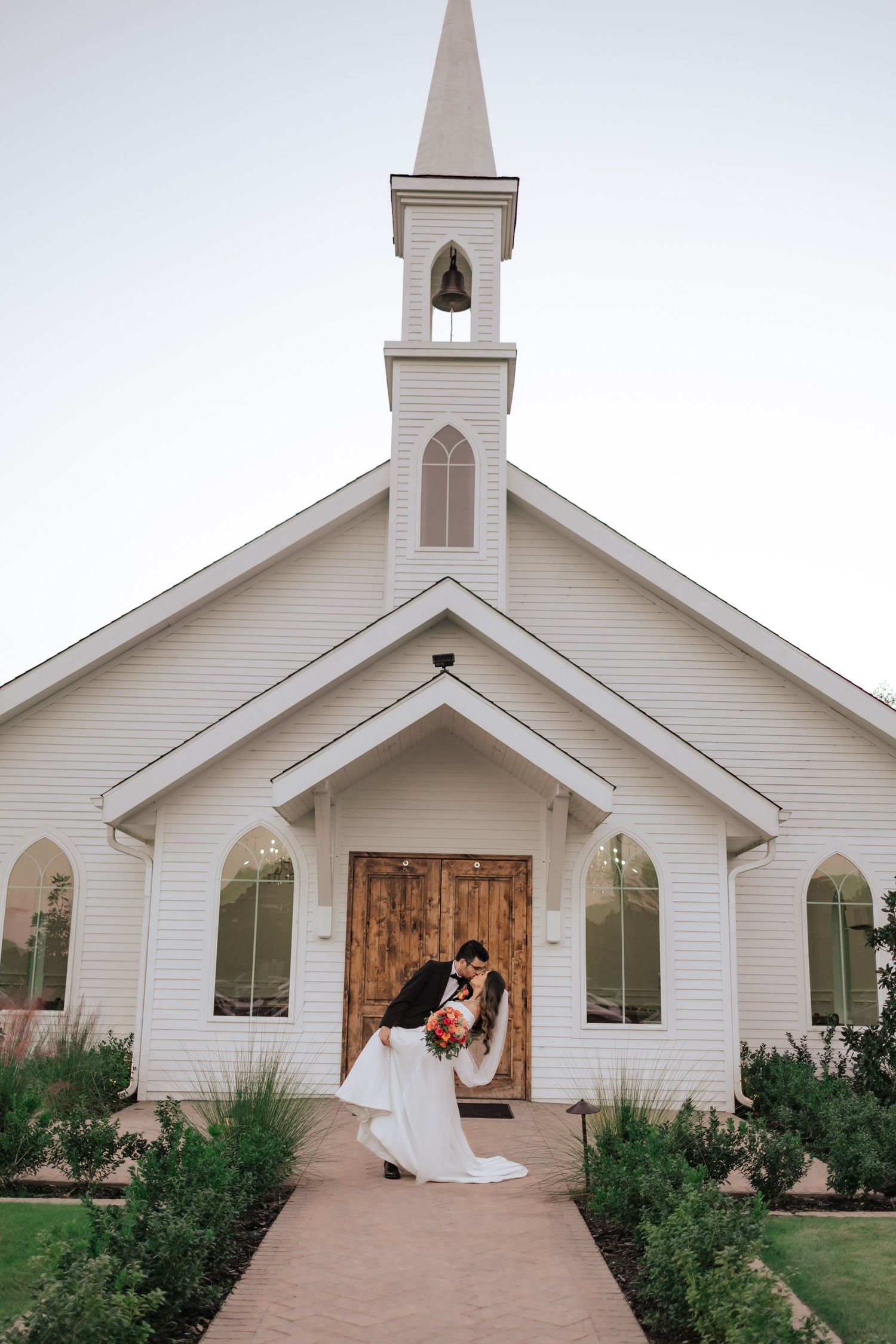 White wooden chapel with gothic arched windows and wooden doors shown from multiple angles at a wedding venue.