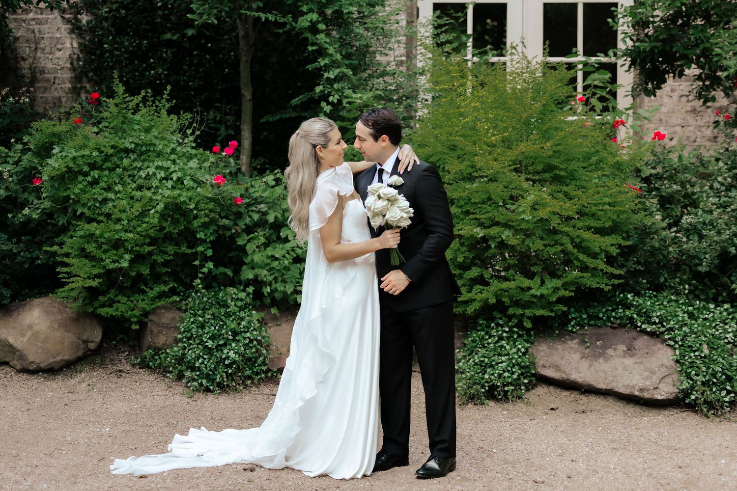 Wedding couple sharing intimate moment in lush garden setting.