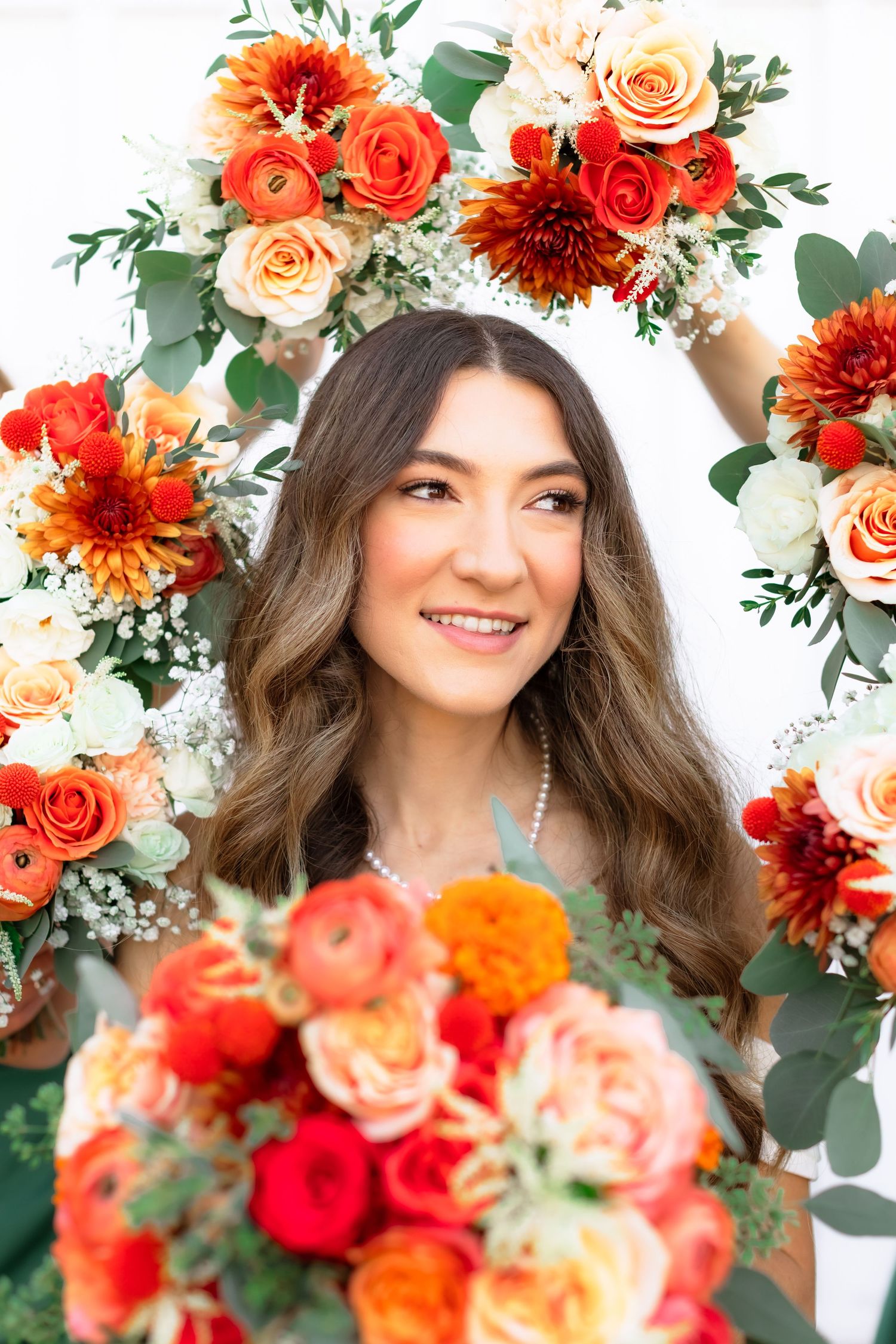 Beautiful autumn wedding bouquet with vibrant orange dahlias, red roses and peach flowers with eucalyptus greenery.