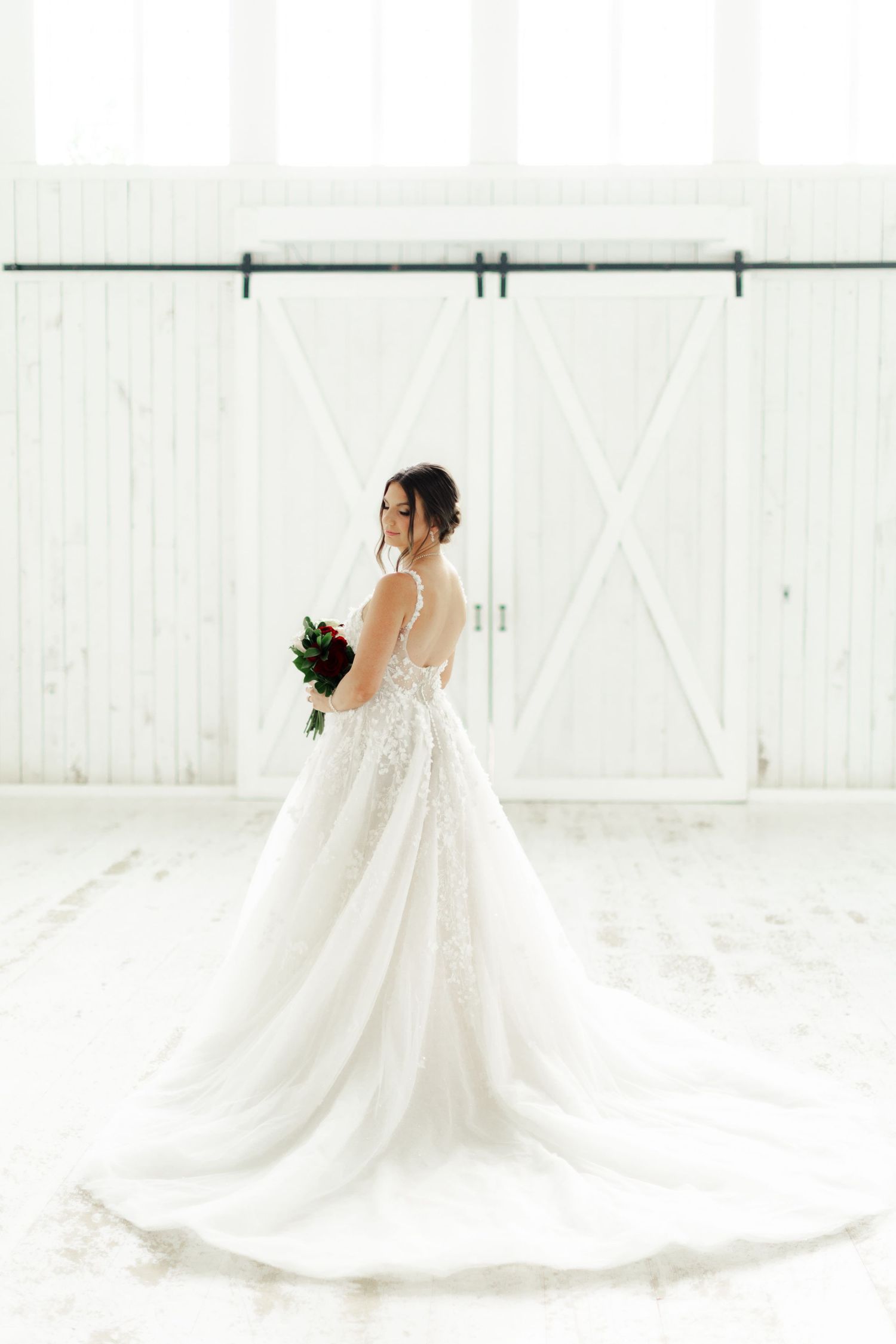 Series of bridal portraits showing the dramatic train of a white wedding gown in a bright white space.