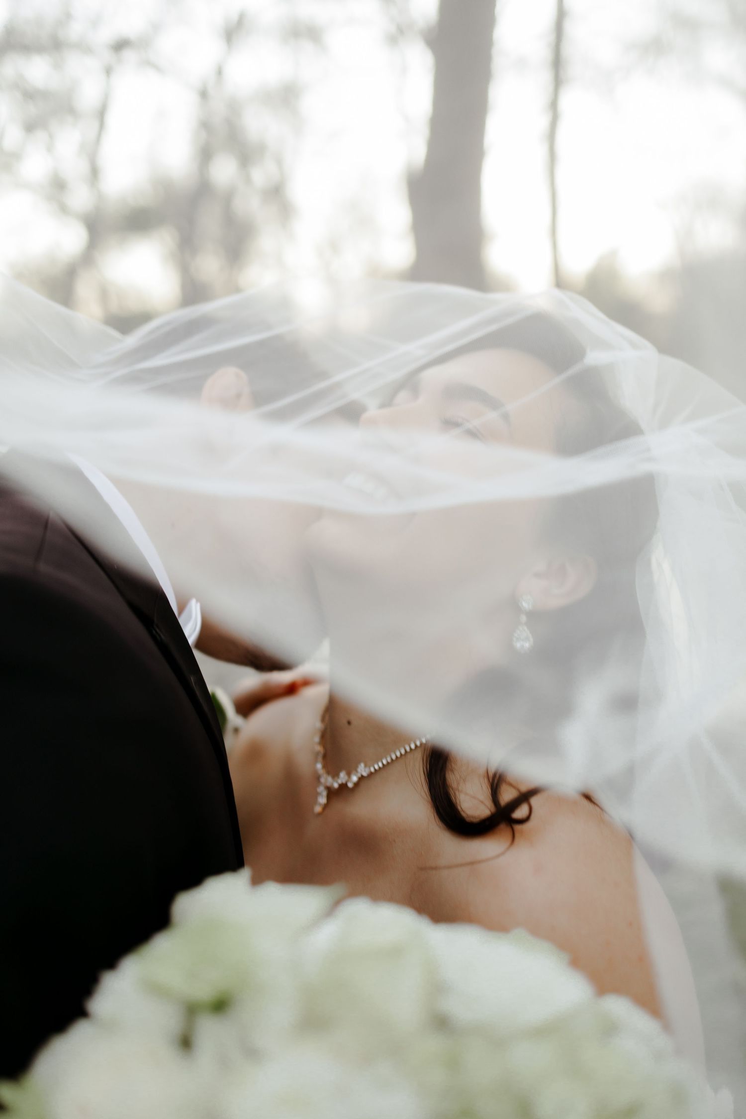 A close-up view of a bride wearing a delicate veil with white flowers in the foreground.
