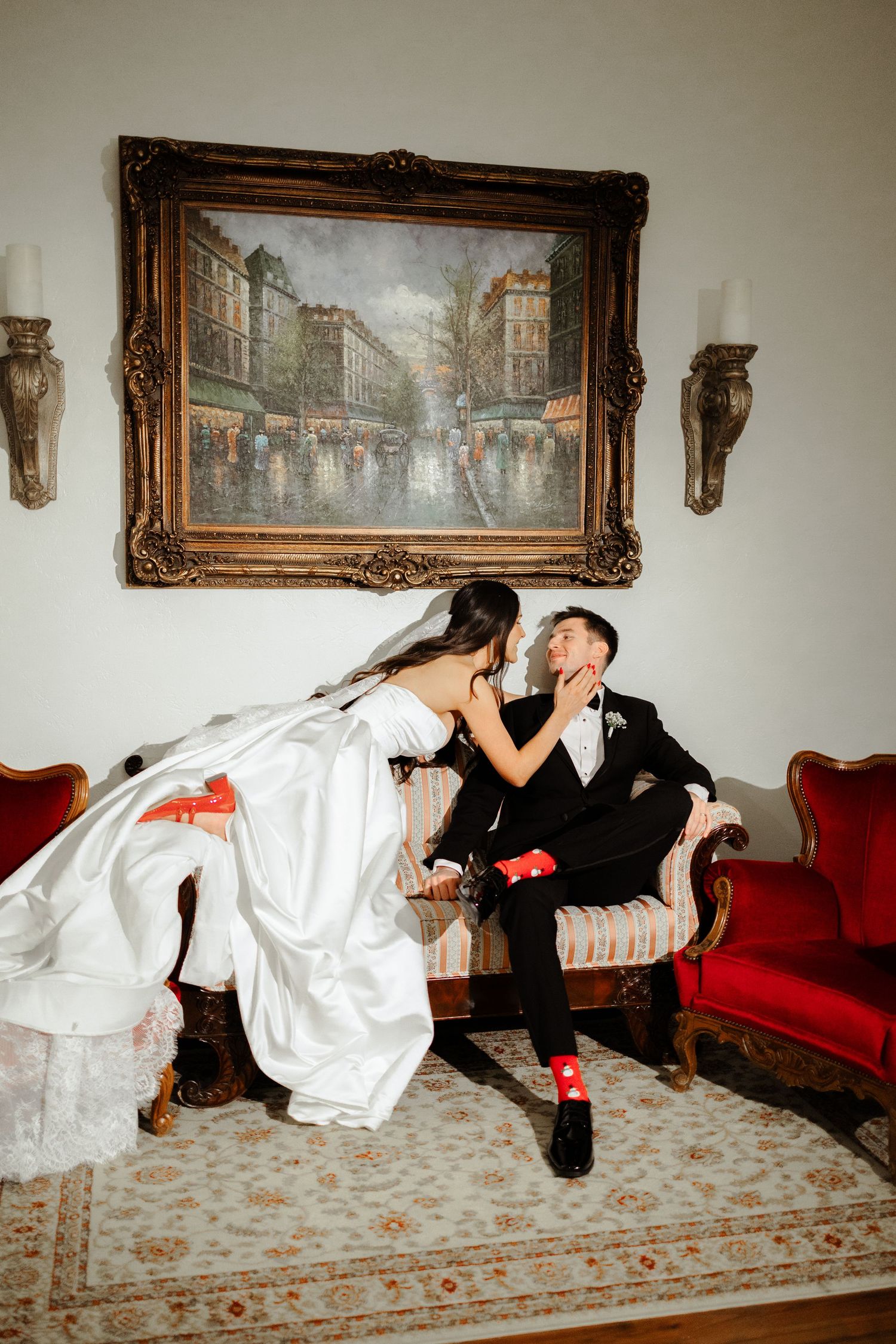 A couple in formal attire performs a playful dance sequence on a carpeted floor beneath framed artwork.