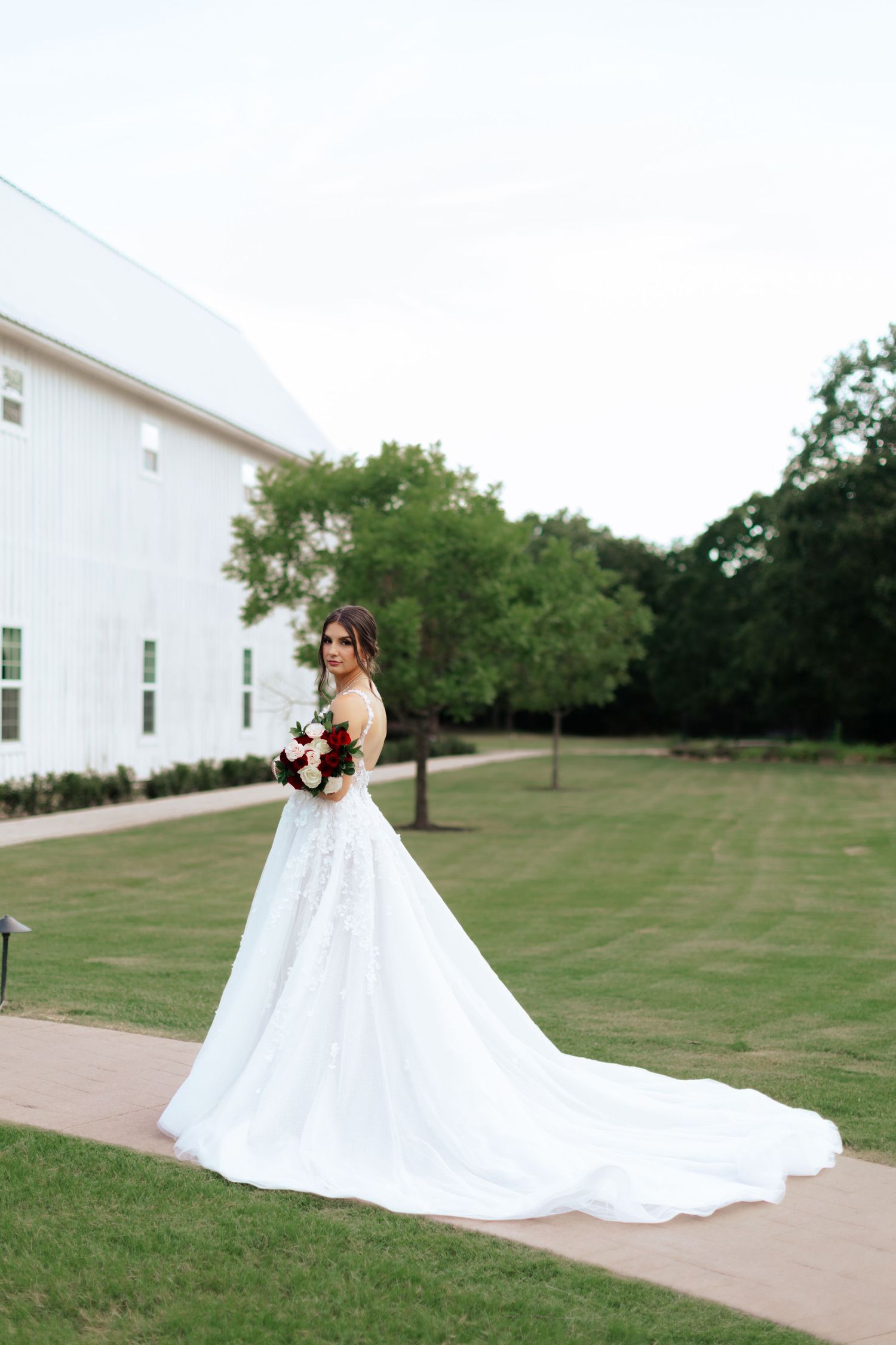 A stunning bridal portrait showcasing a long train wedding dress against a white chapel backdrop.