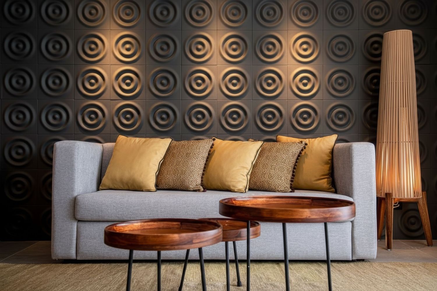 Modern living room with gray sofa, gold throw pillows, copper coffee tables, and a decorative 3D circle pattern accent wall.