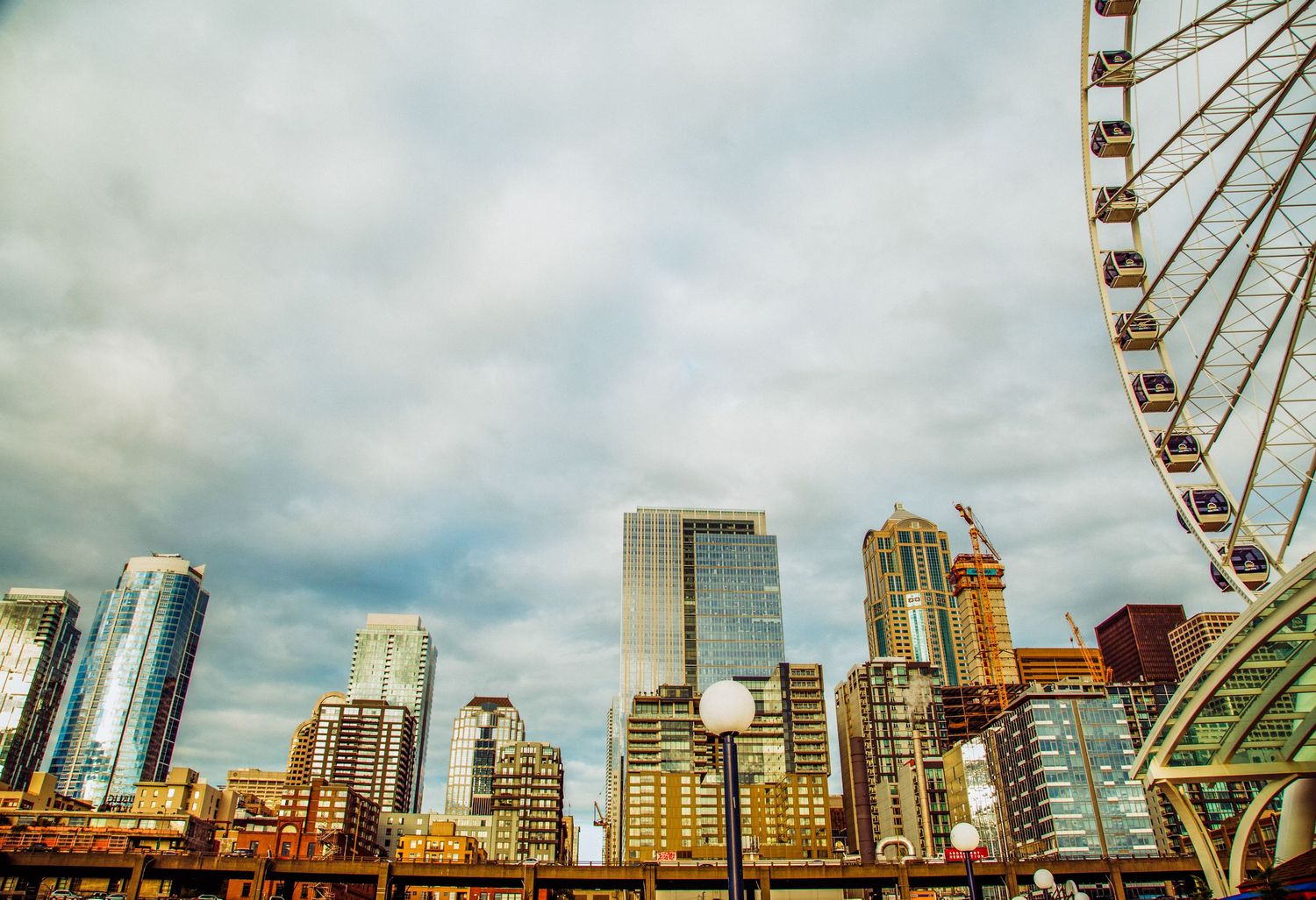 Seattle skyline with skyscrapers and a Ferris wheel under cloudy skies.