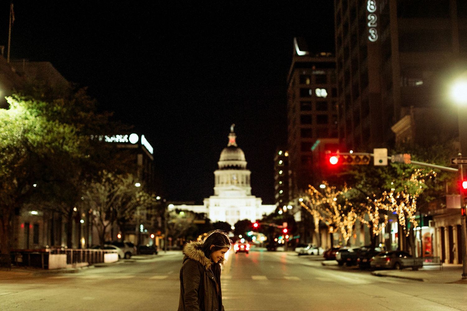Couple kissing on Congress Avenue at night with the illuminated Texas State Capitol building in the background.
