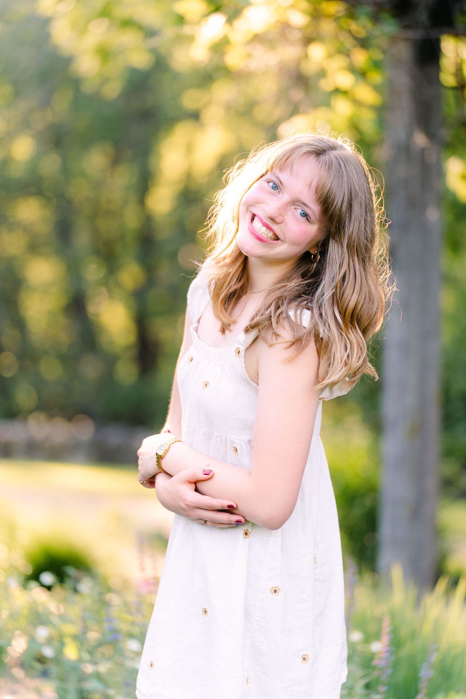 Senior girl bathed in golden light at Noerenberg Gardens, surrounded by tall grass and sunset warmth.