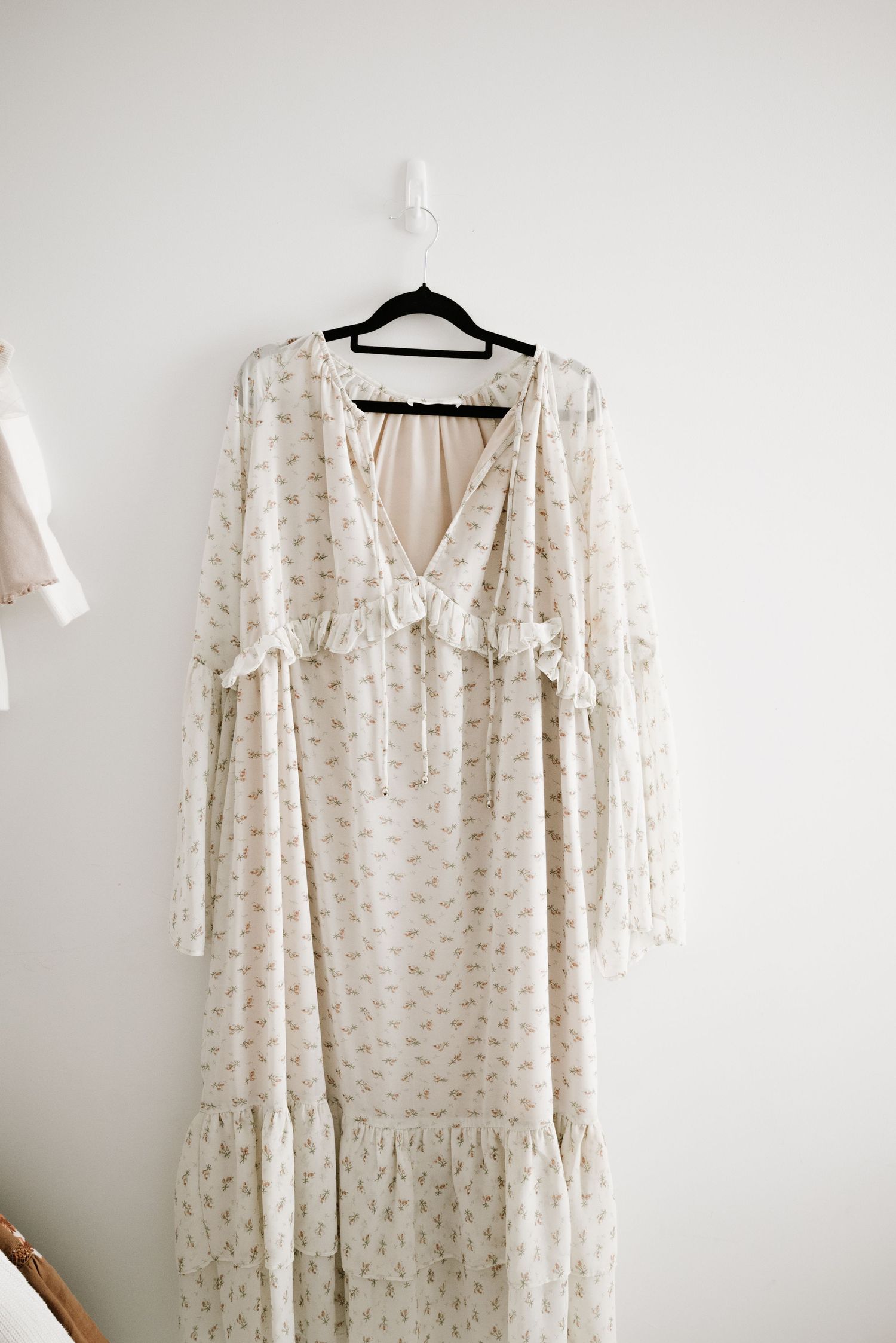 A vintage-inspired cream maxi dress with ruffle details and bell sleeves on display.