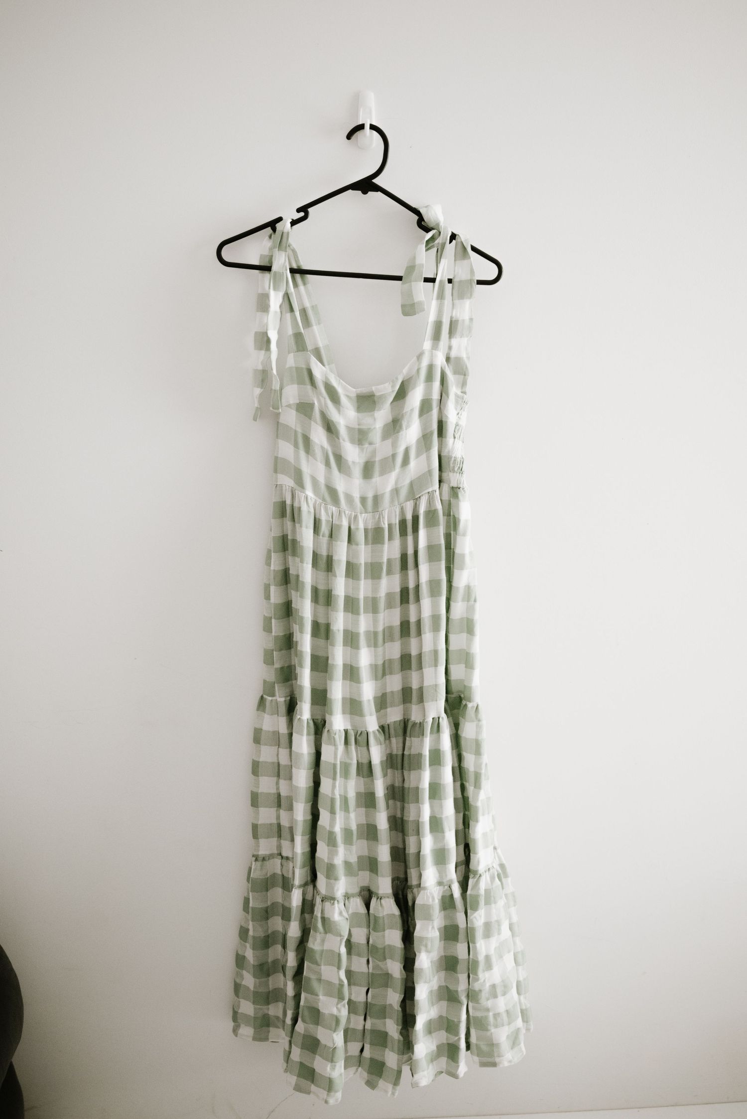 Green and white gingham maxi dress with tiered skirt hanging on black hanger.