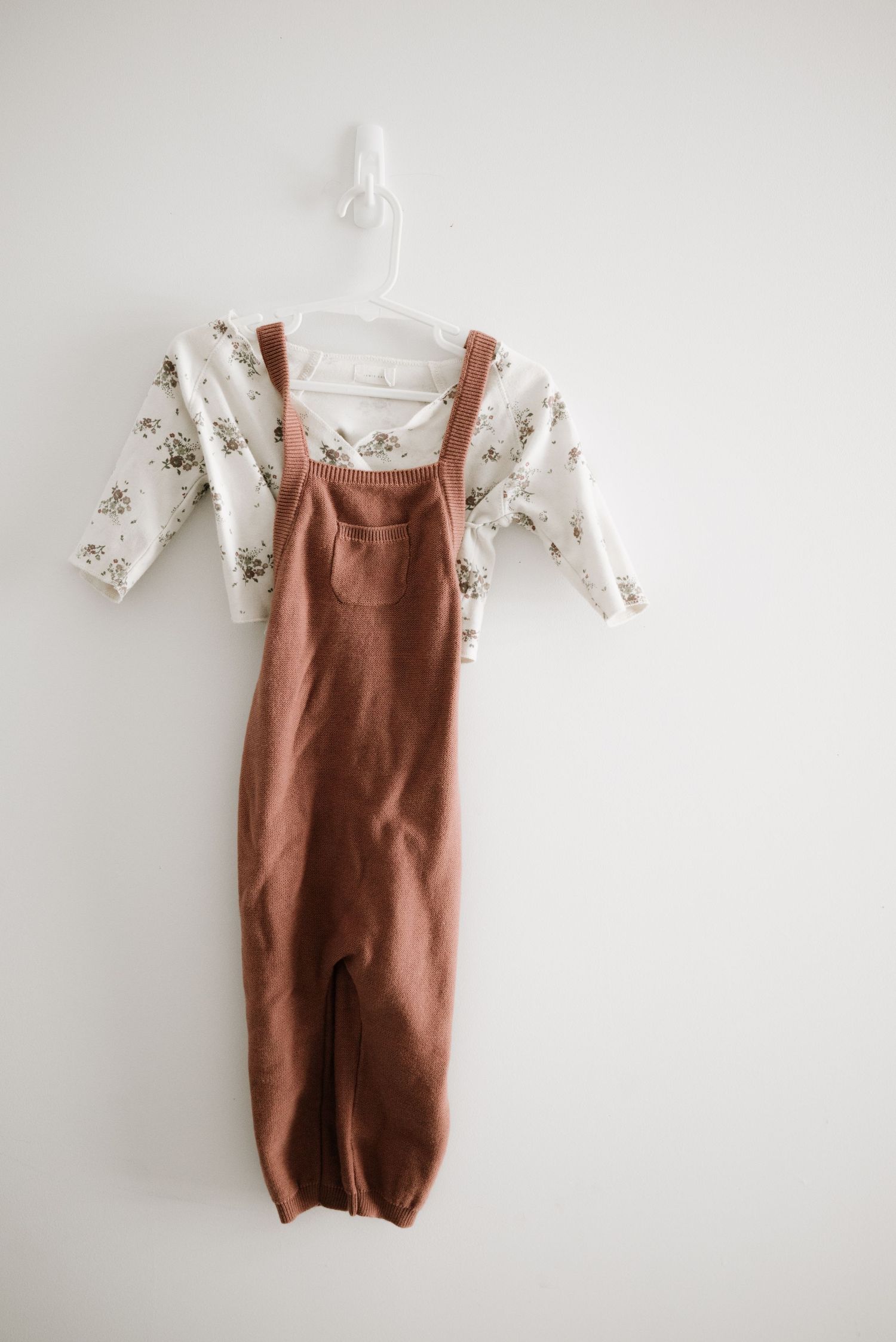 Brown corduroy overalls paired with a floral print long sleeve shirt for children.