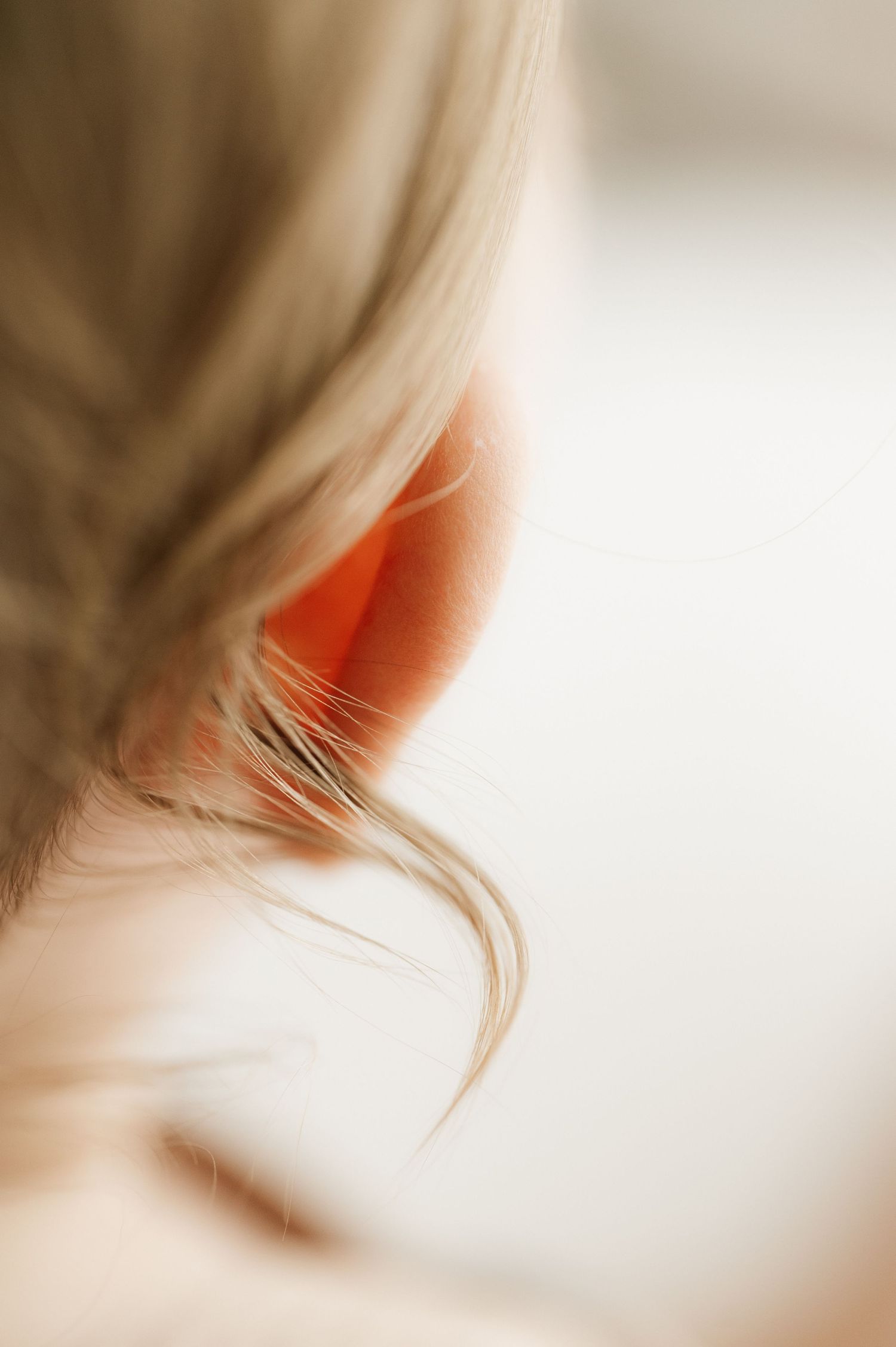 Artistic macro shot of blonde hair and ear in soft focus.