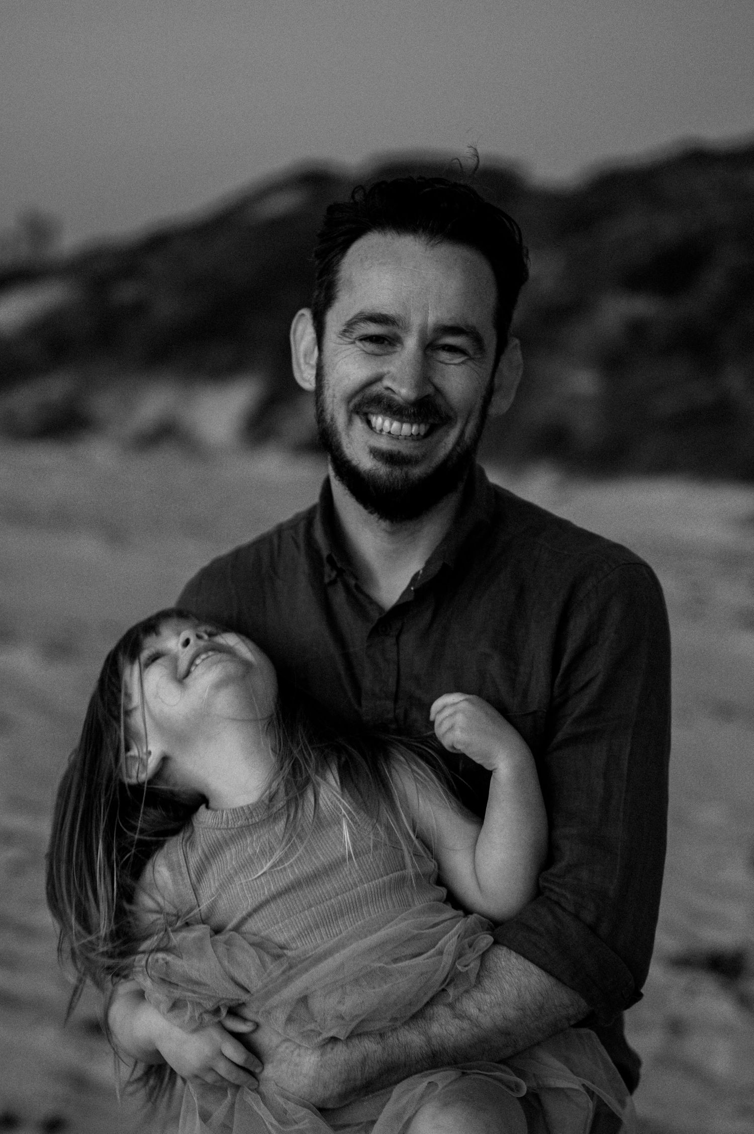 Black and white portrait showcasing playful and joyful moments during beach photoshoot.
