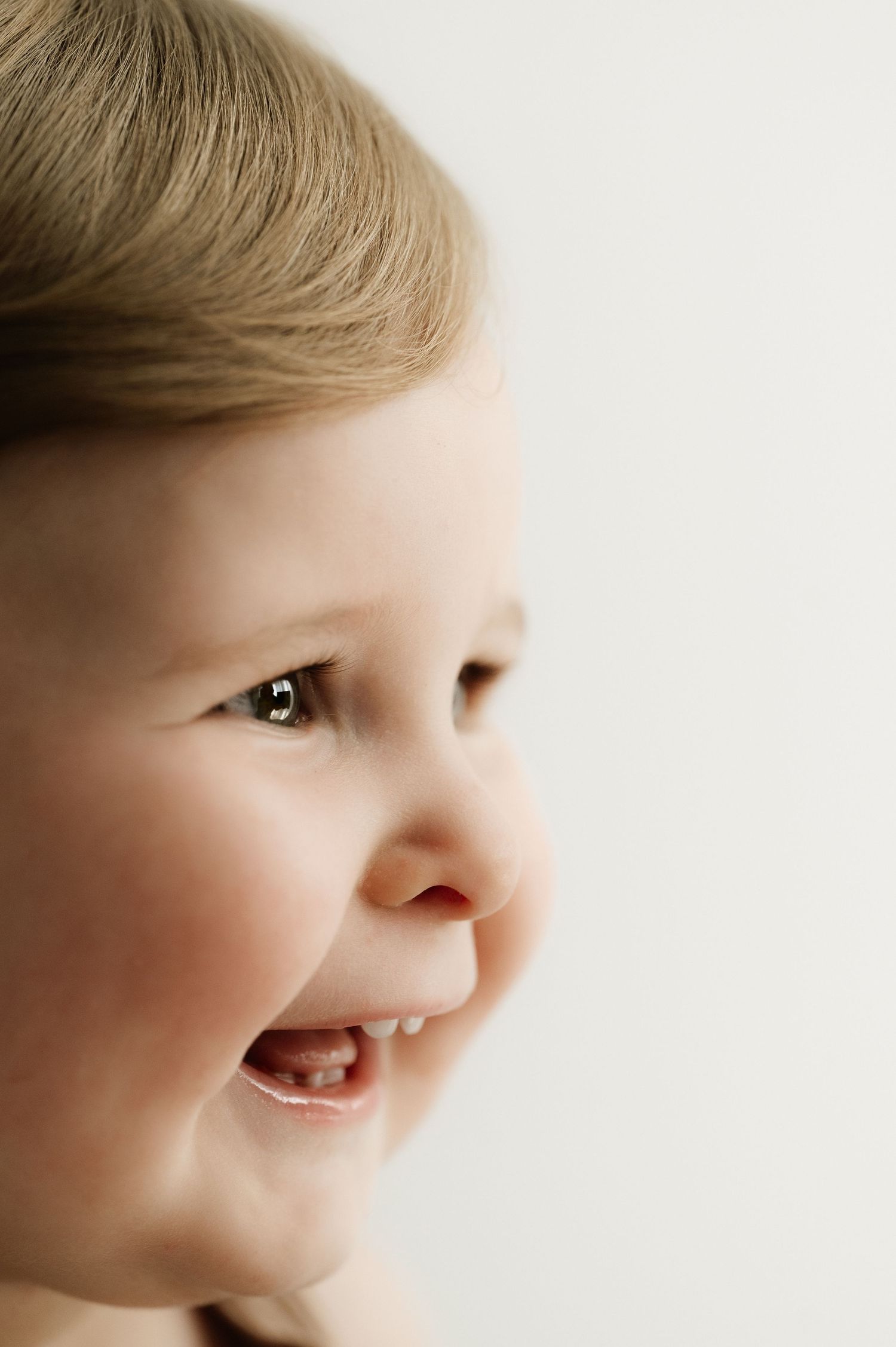 Close-up profile of a smiling young child against a white background.