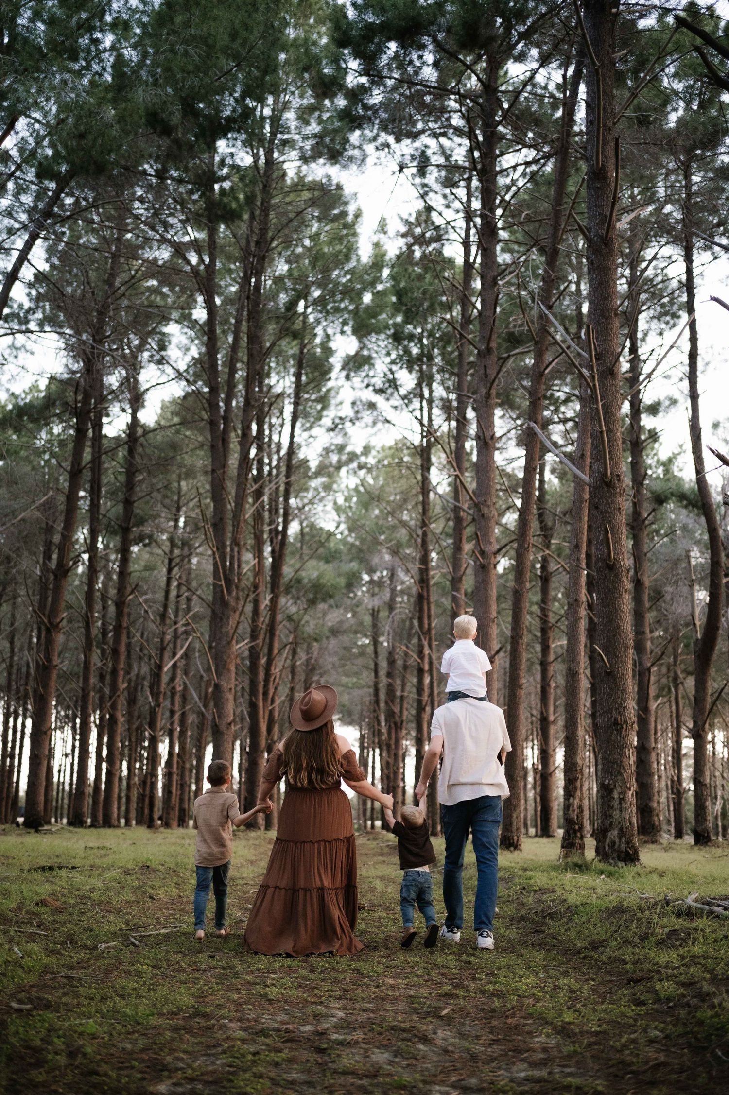 Family spending time together in a serene pine forest with tall trees creating a natural walkway.