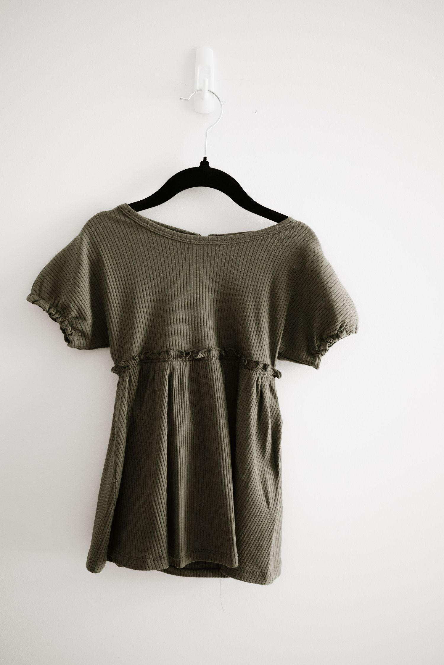 Olive green ribbed top with empire waist and short flutter sleeves on black hanger.